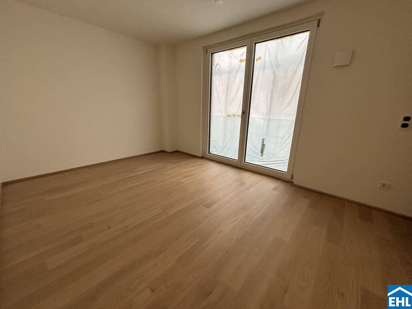 Heller Raum mit Parkettboden und großem Fenster, bereit zur individuellen Gestaltung.