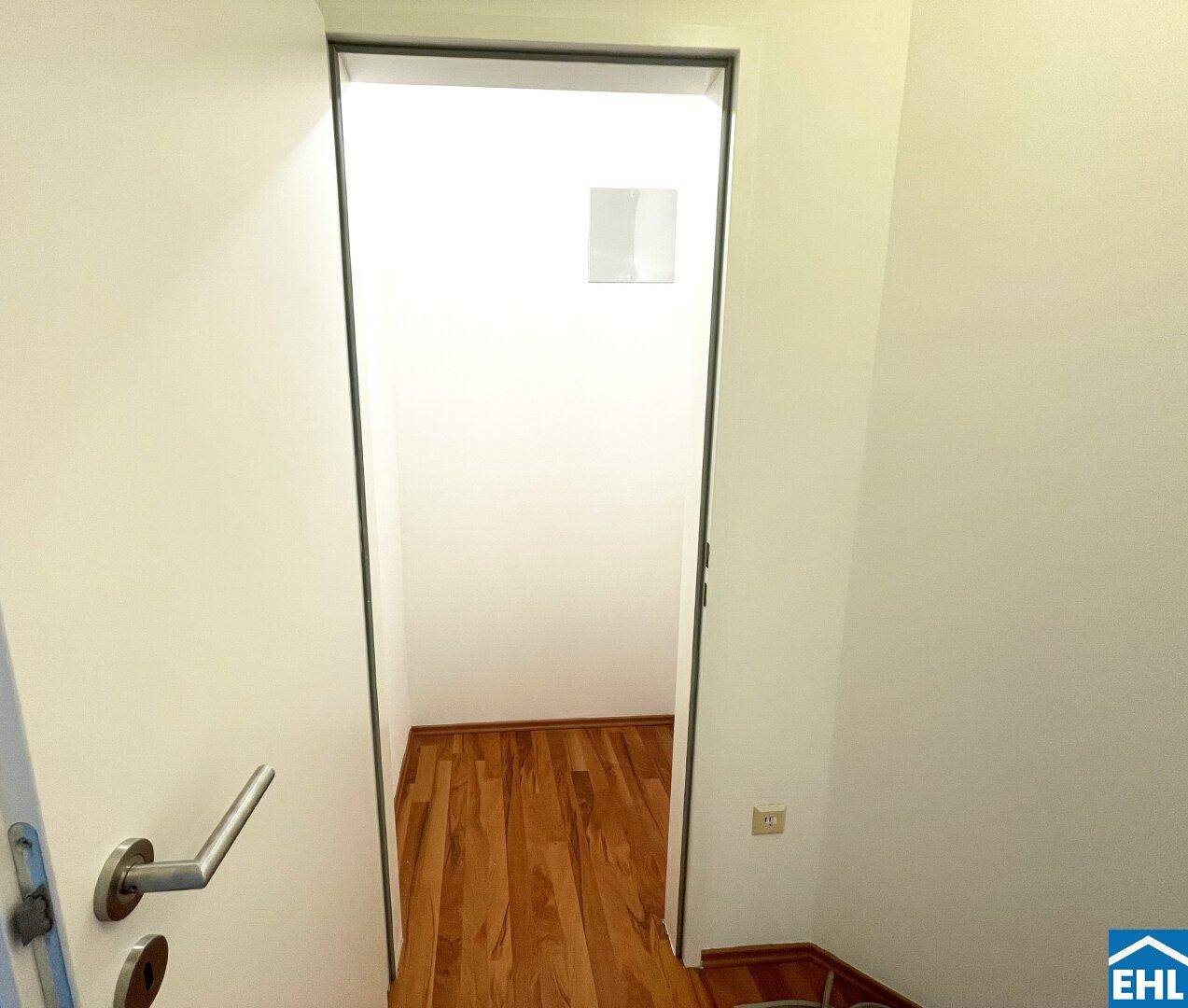 Offener Türrahmen führt in einen weiteren Raum mit Laminatboden, schlicht und funktional.