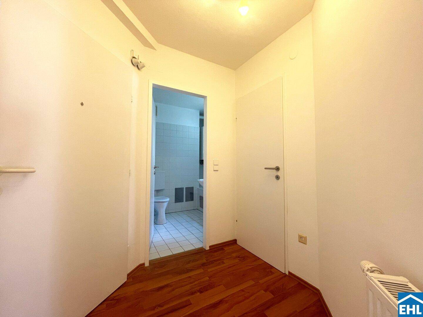 Heller Flur mit Laminatboden und Zugang zum Badezimmer, schlicht und funktional.