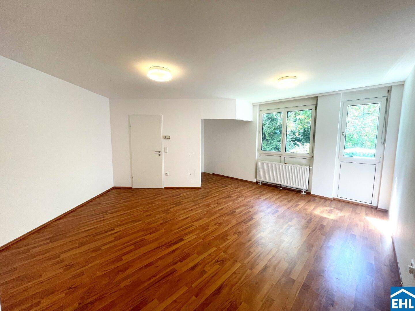 Freundliches Zimmer mit Laminatboden und Zugang zu einem weiteren Bereich, hell und einladend.