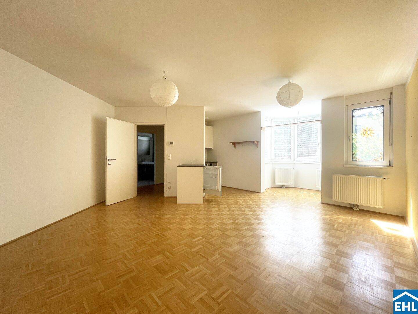Geräumiger Wohnbereich mit Parkettboden, viel Tageslicht und Zugang zu weiteren Räumen.