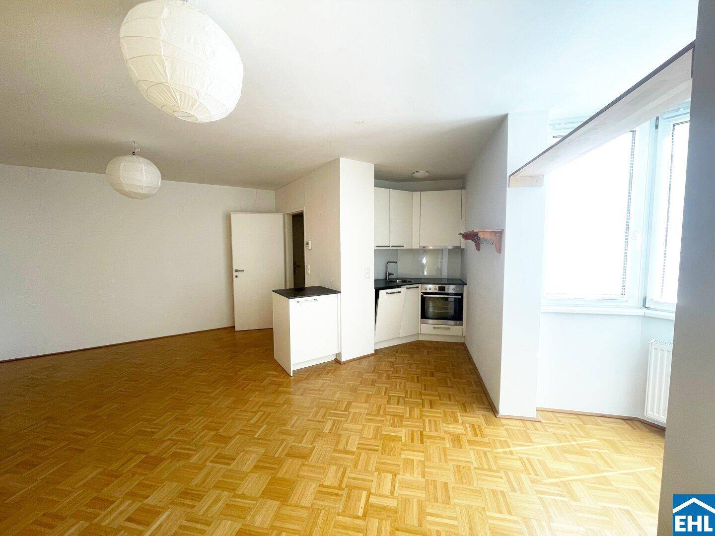 Funktionale Küchenzeile im Wohnbereich mit weißen Schränken und integriertem Backofen.
