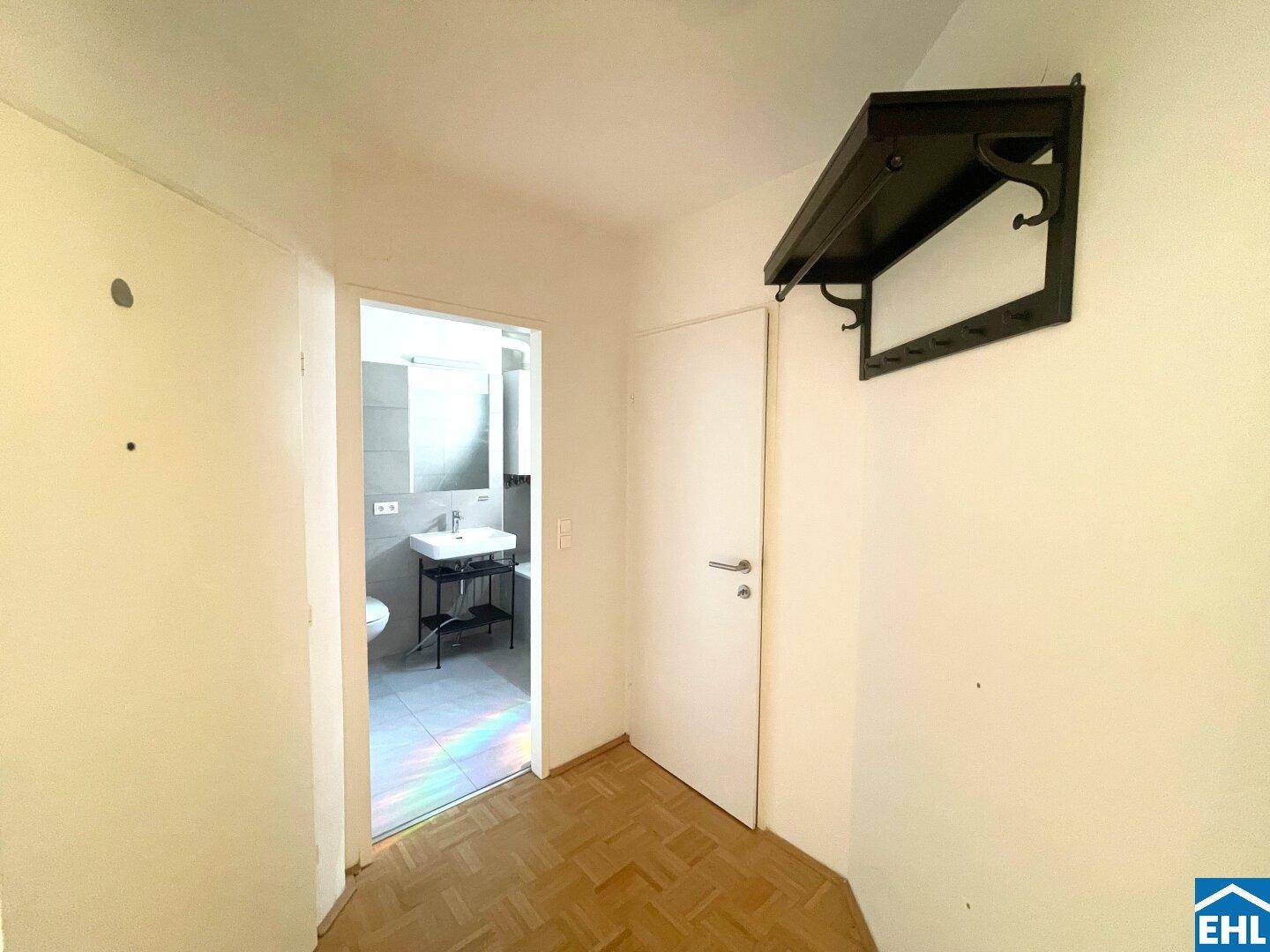 Heller Flur mit Parkettboden und Garderobe, der zum Badezimmer führt.