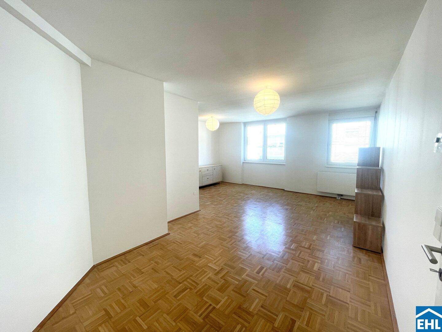 Geräumiges Schlafzimmer mit Parkettboden und großen Fenstern, bietet viel Tageslicht.