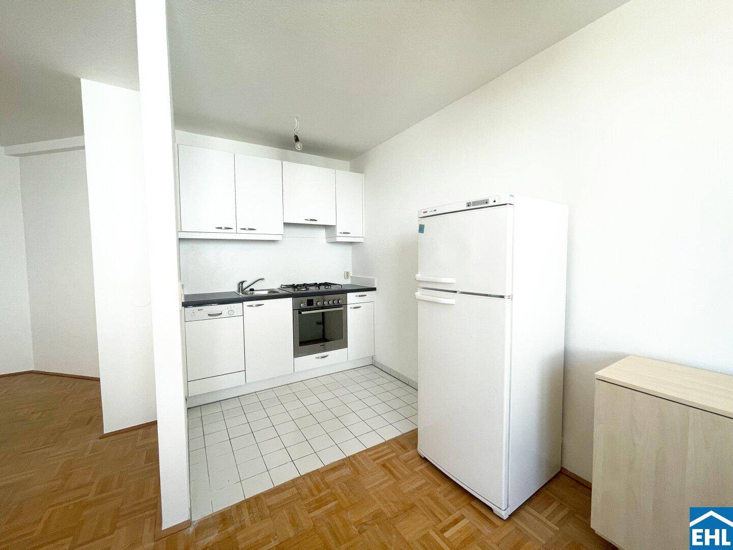 Kompakte Küchenzeile mit weißen Schränken, Gasherd, Backofen und Kühlschrank.