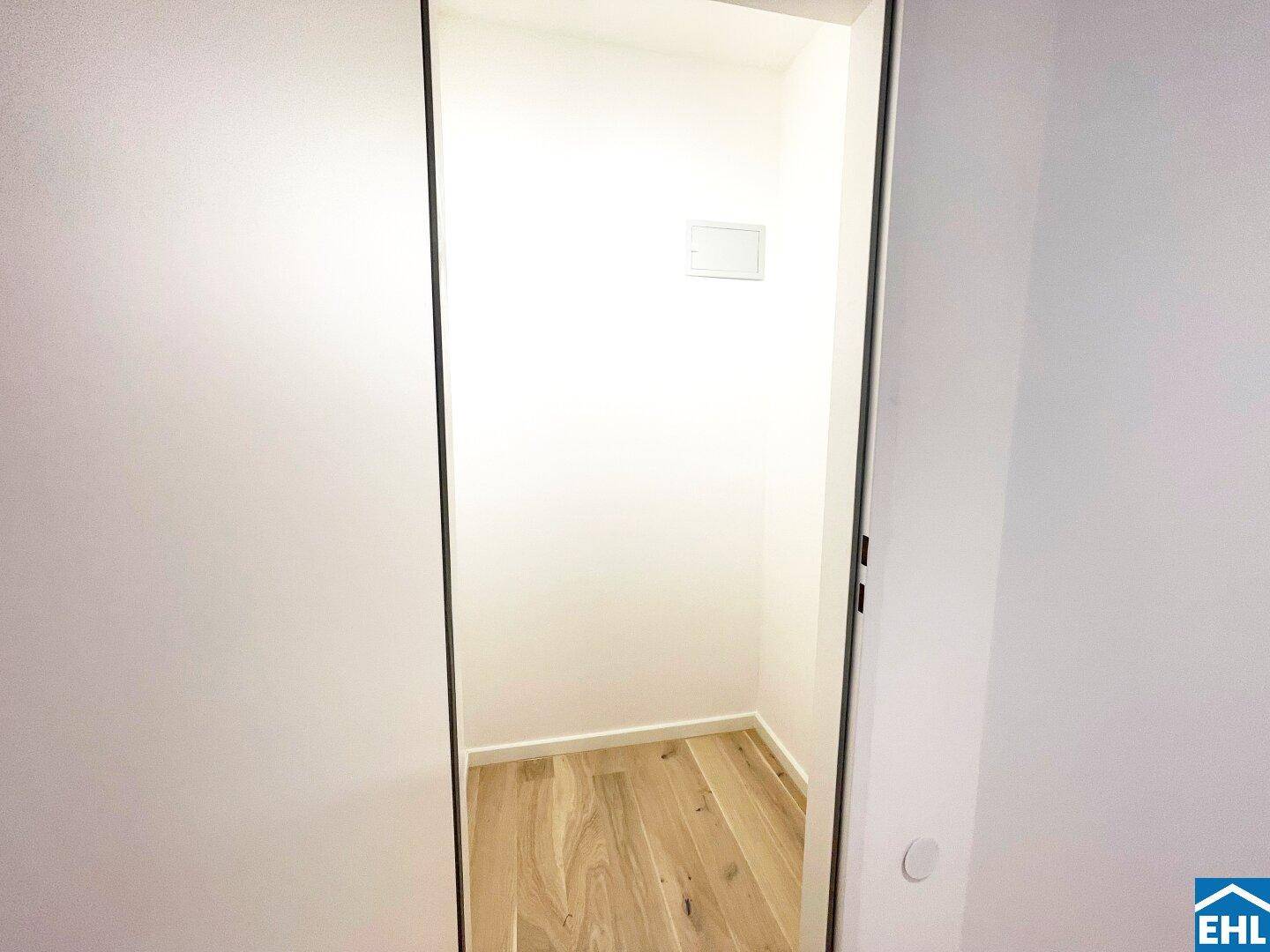 Praktischer Abstellraum mit Holzboden und weißen Wänden.