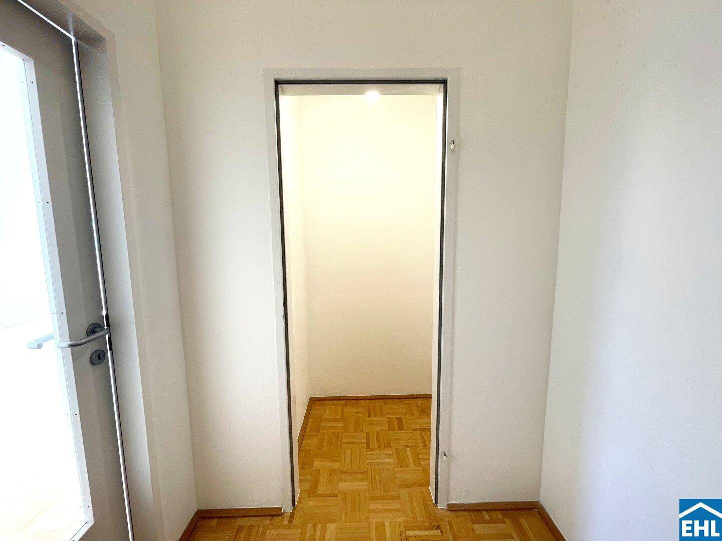 Eingangsbereich mit Parkettboden und Blick in einen weiteren Raum der Wohnung.