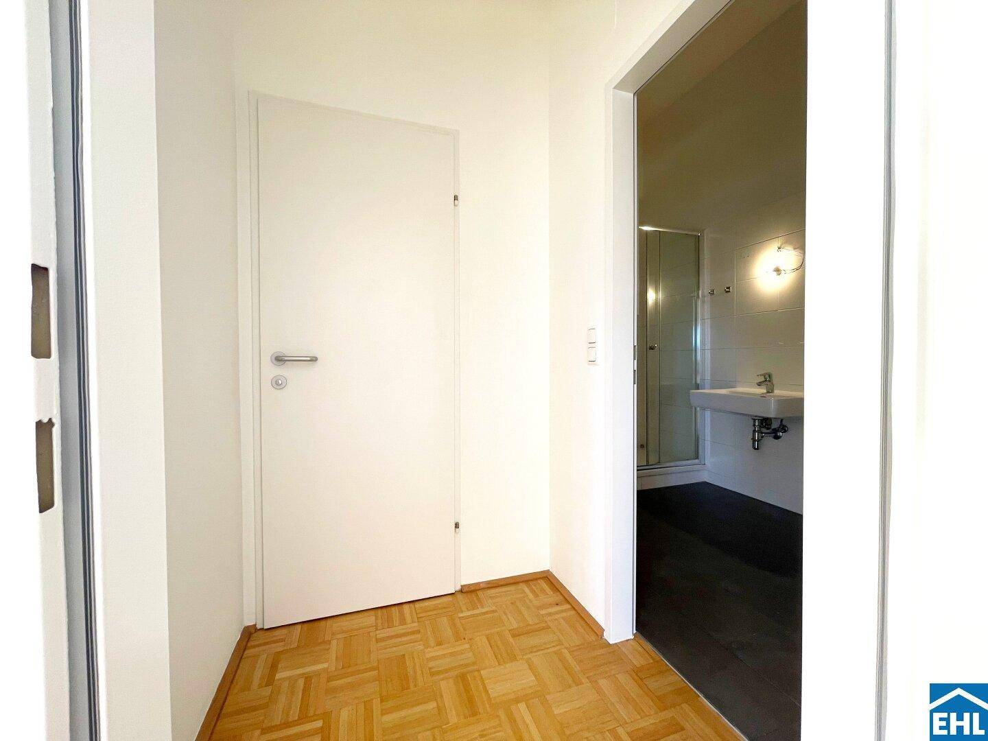 Heller Flur mit Parkettboden und Zugang zum Badezimmer, gut gepflegt.