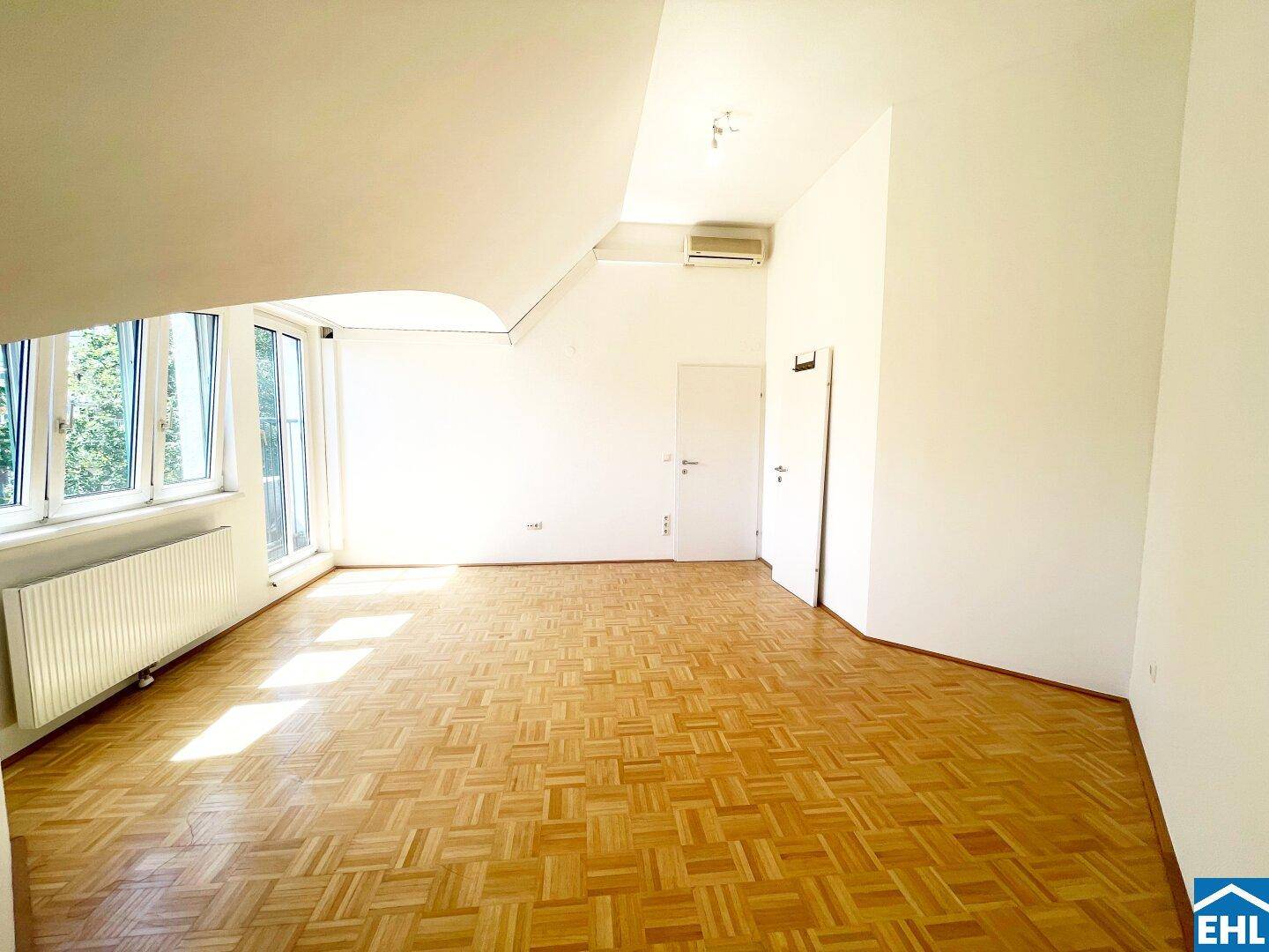Geräumiger Wohnbereich im Dachgeschoss mit Parkettboden, Klimaanlage und viel Tageslicht.