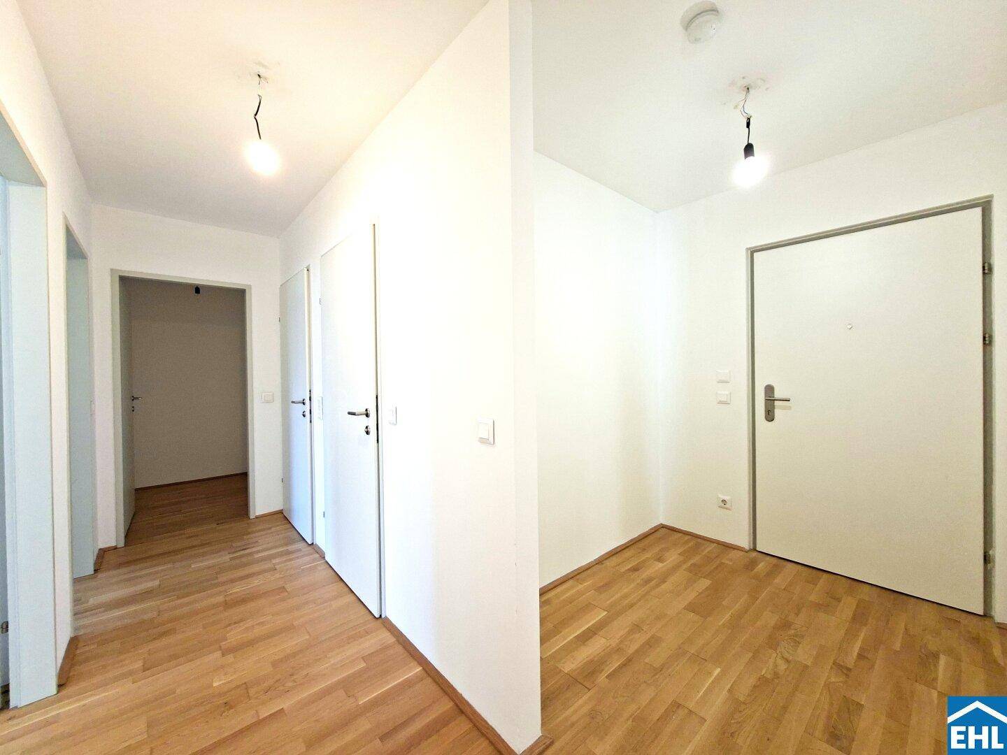 Heller Eingangsbereich mit Holzboden und mehreren Türen, die zu den Zimmern führen.