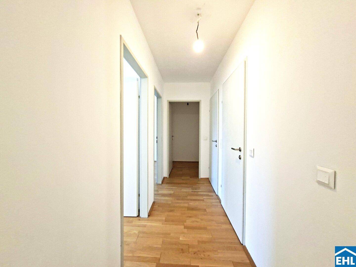 Langer Flur mit hellem Parkettboden und weißen Türen, der die verschiedenen Räume verbindet.