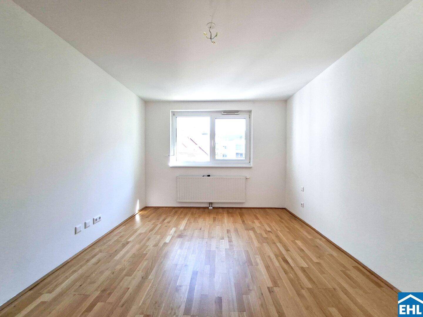 Geräumiges Zimmer mit hellem Holzboden und viel Tageslicht durch das Fenster.