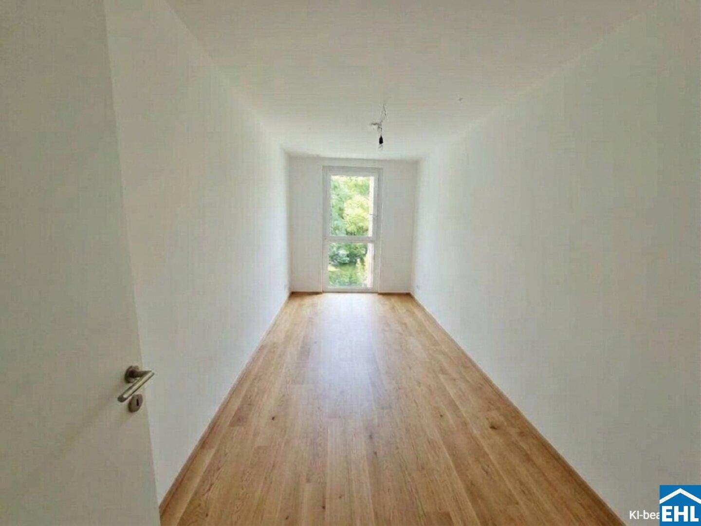 Helles Zimmer mit Holzboden und einer Fenstertür, die Zugang zum Außenbereich bietet.