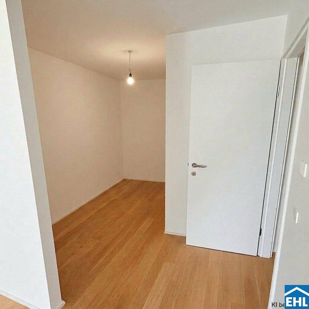 Heller Innenraum mit Parkettboden und weißer Tür, bietet Zugang zu einem weiteren Bereich.