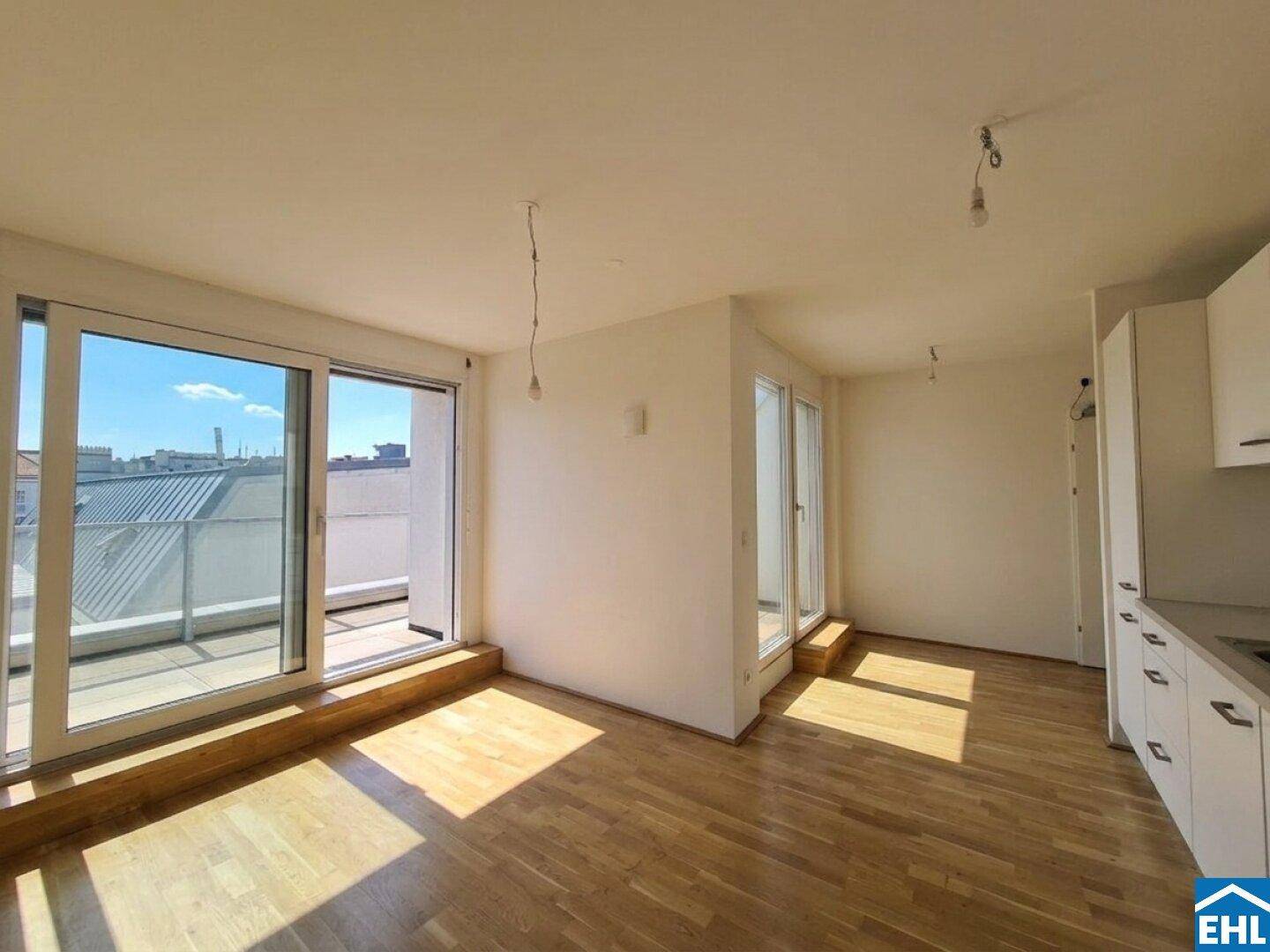 Sonniger Wohnraum mit Holzboden und direktem Zugang zur großzügigen Dachterrasse.