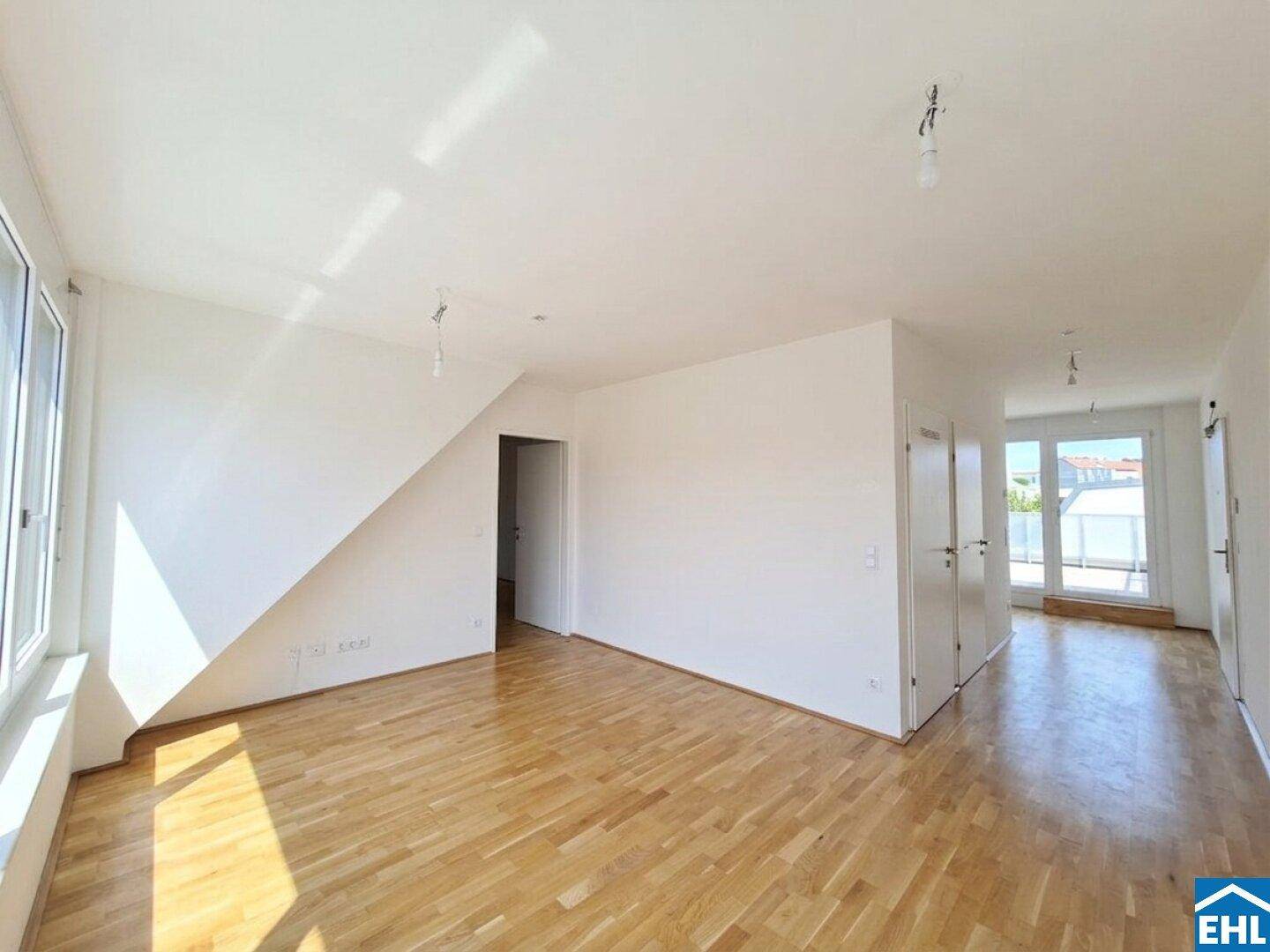 Lichtdurchfluteter Wohnbereich mit Holzboden und Zugang zu einem Außenbereich.