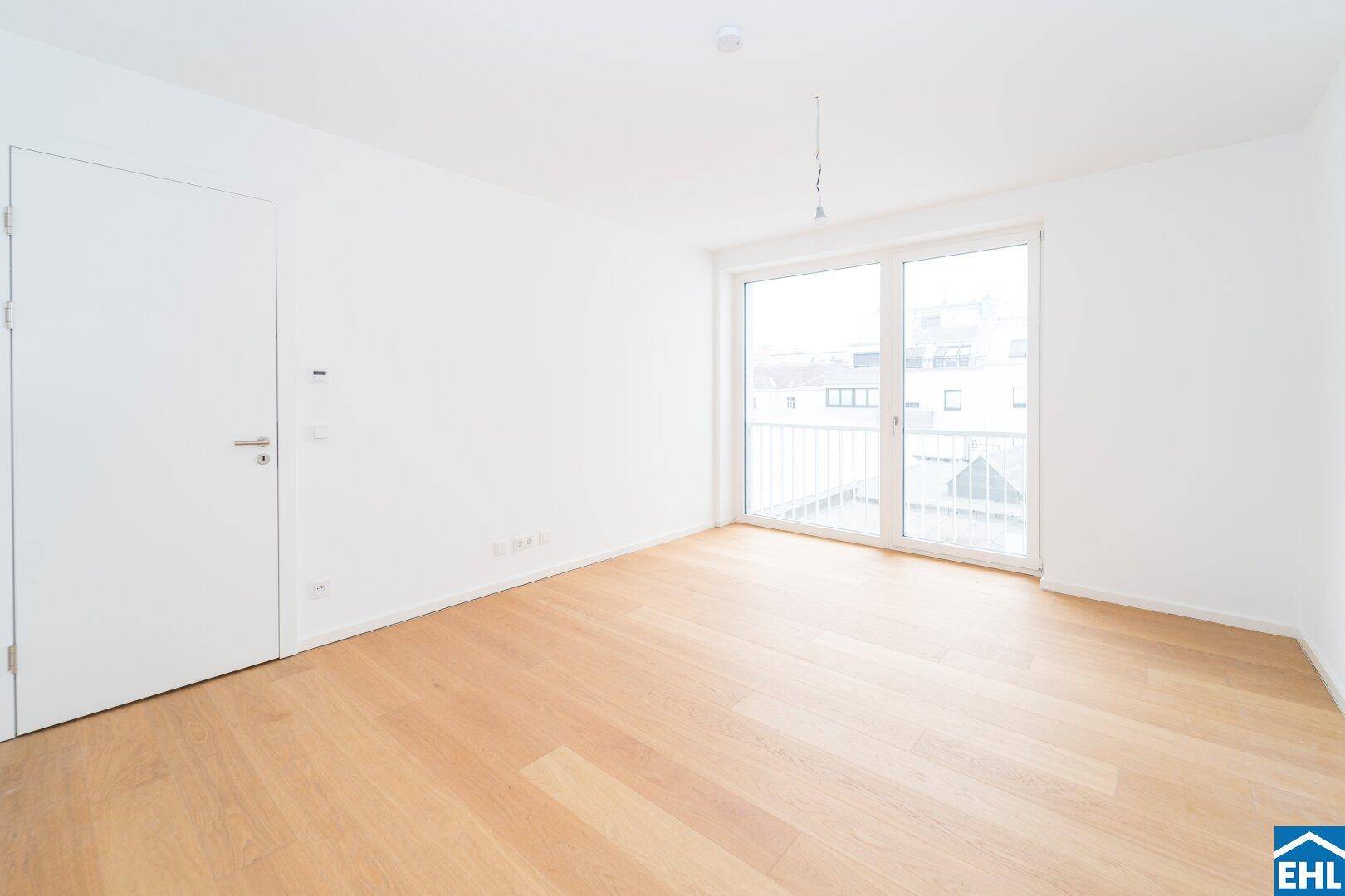 Geräumiges Schlafzimmer mit hellem Holzboden und Zugang zu einem Außenbereich durch eine große Tür.