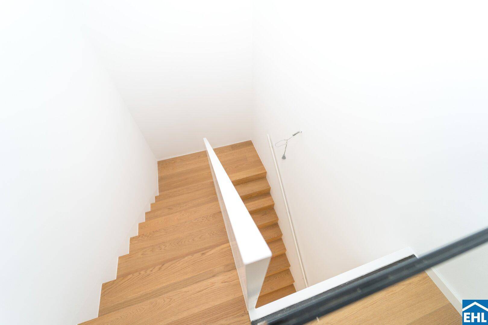 Moderne Holztreppe mit minimalistischem Geländer, die die verschiedenen Ebenen des Hauses verbindet.
