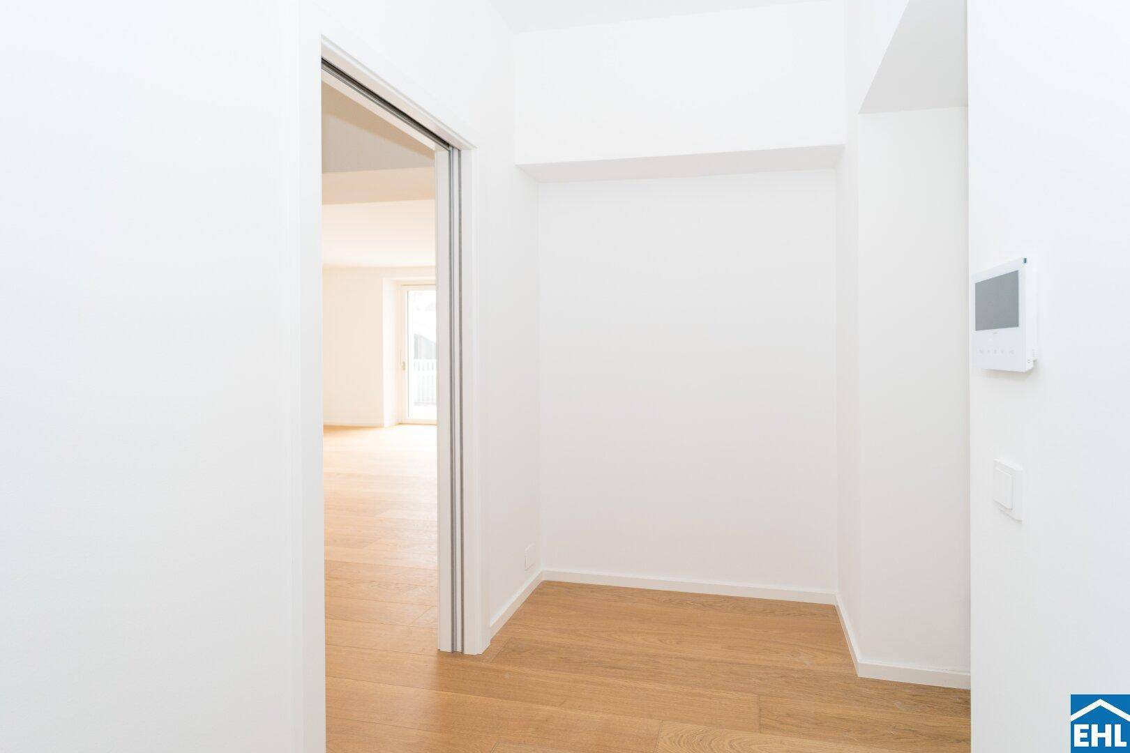 Heller Flurbereich mit Holzboden und einer Nische, die als Garderobe oder Abstellraum dienen könnte.