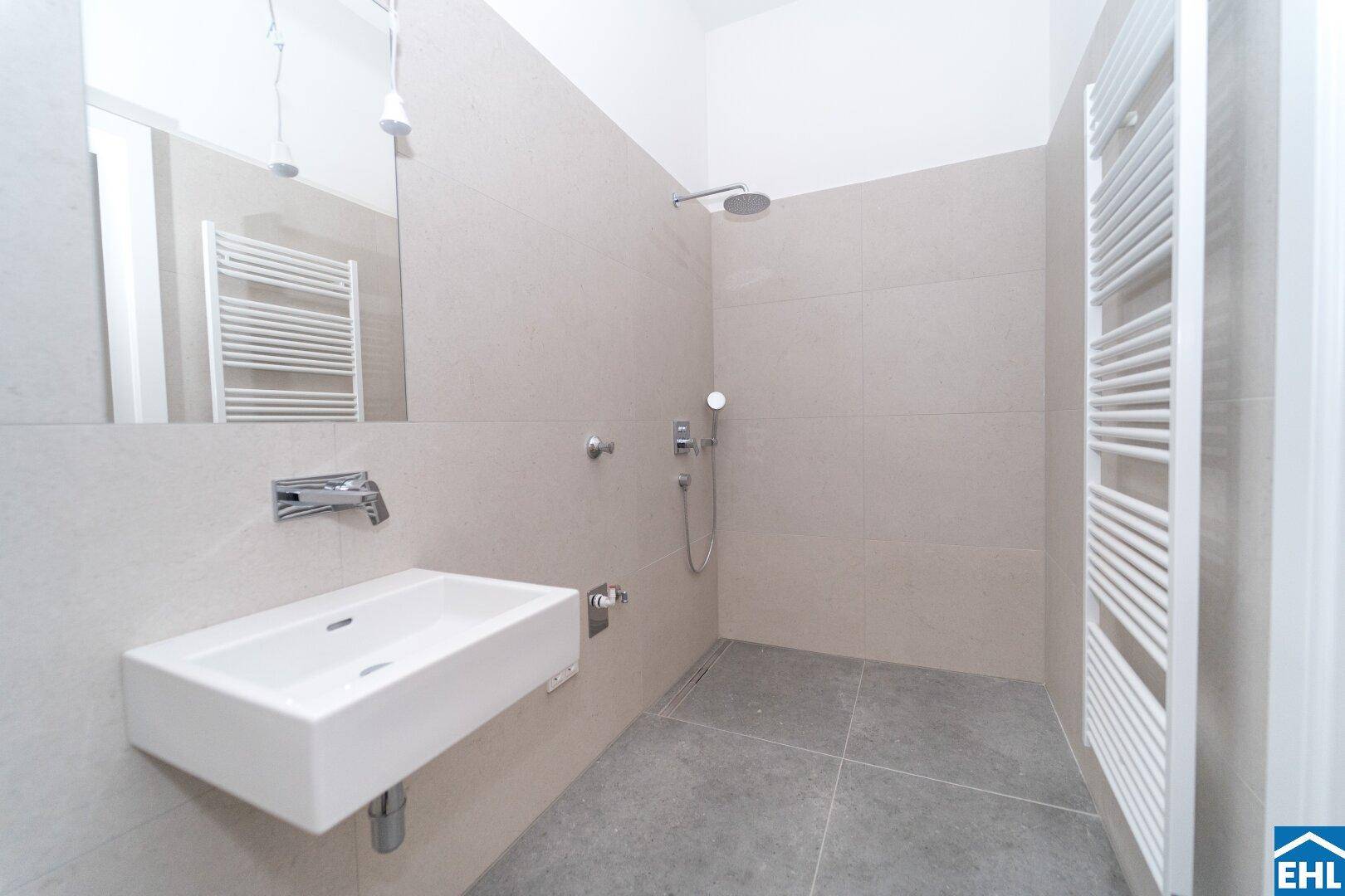 Modernes Badezimmer mit ebenerdiger Dusche, Wandwaschbecken und beheiztem Handtuchhalter.