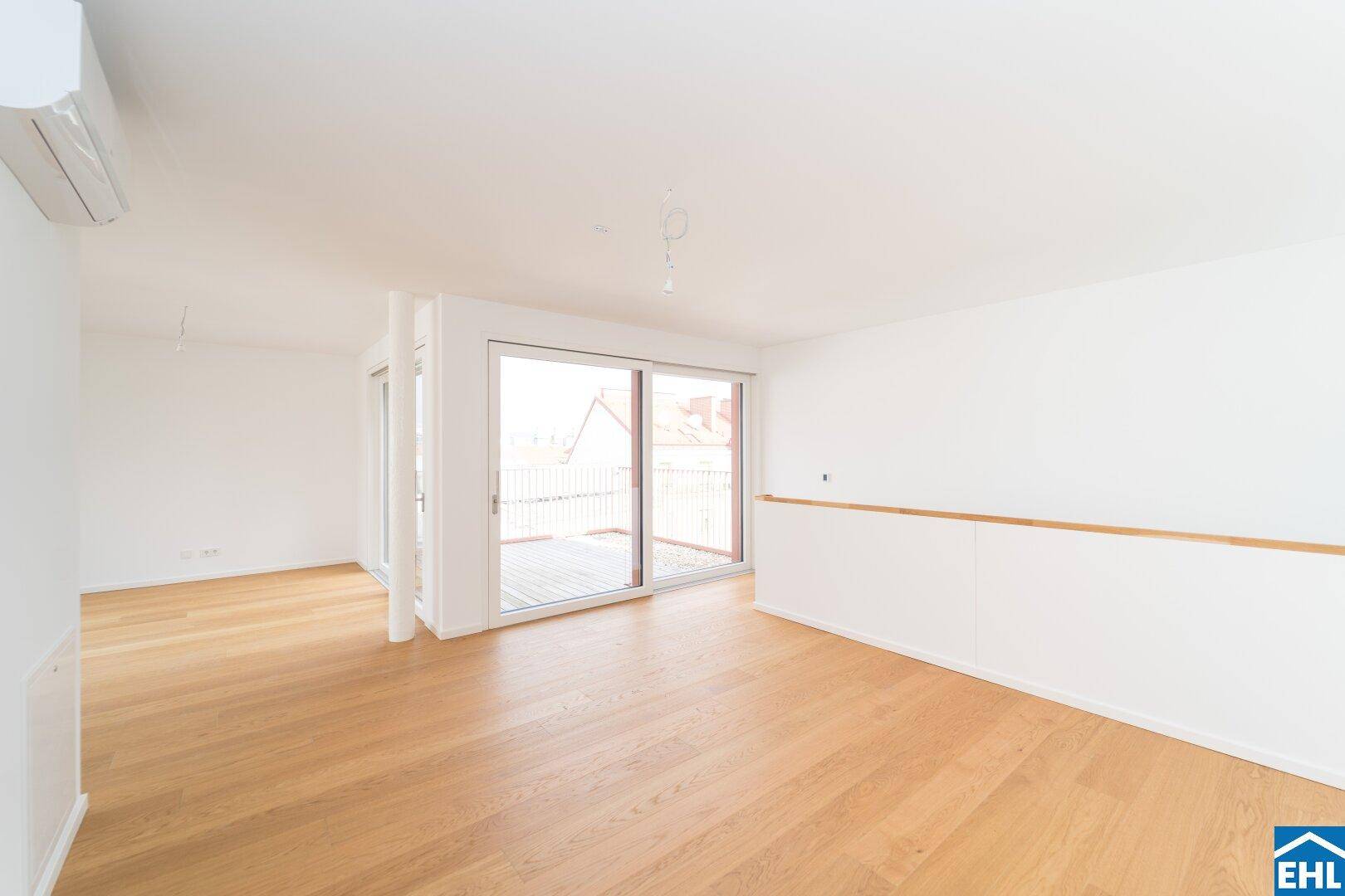Lichtdurchfluteter Wohnbereich mit Holzboden, Klimaanlage und Zugang zu einer Terrasse.