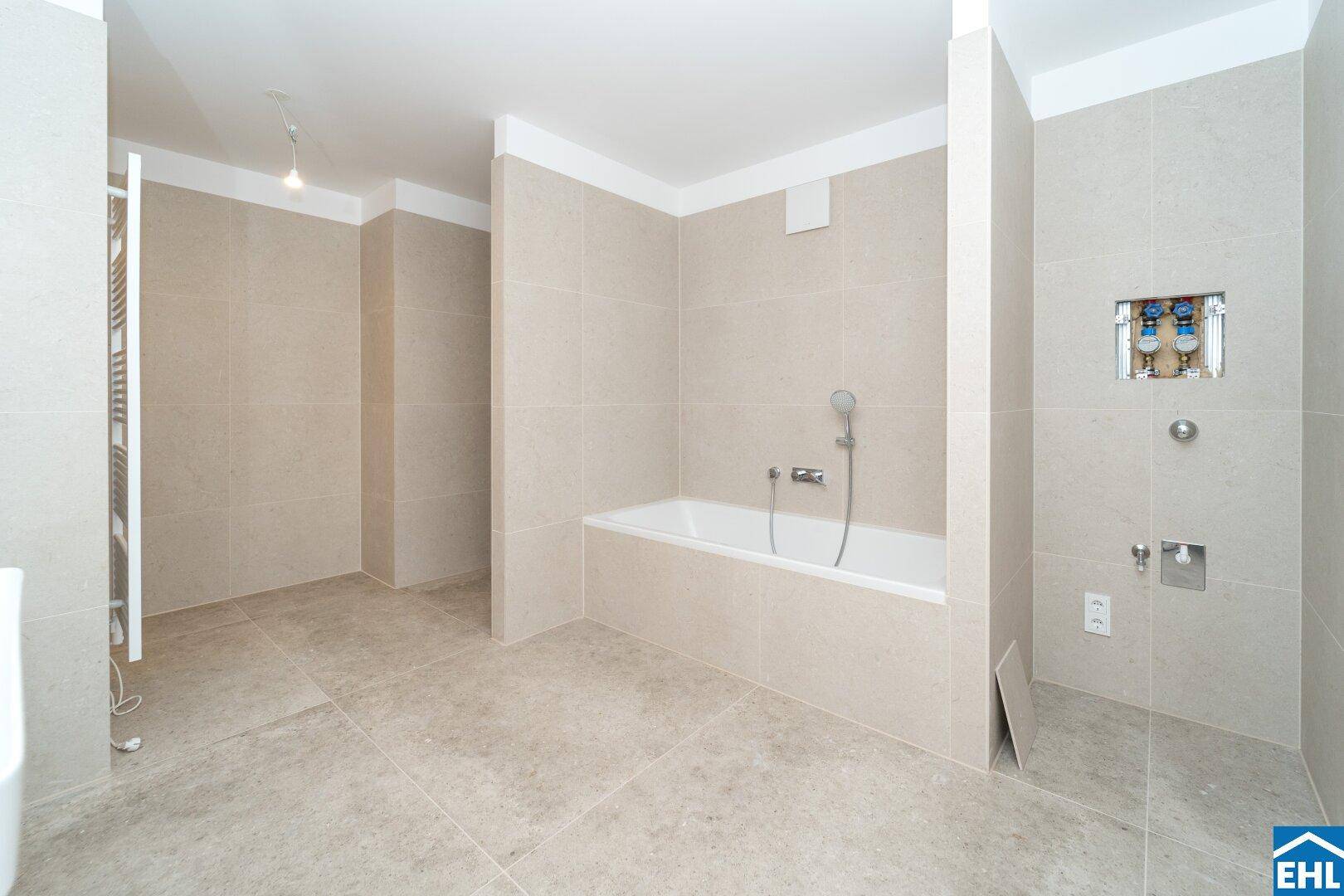 Modernes Badezimmer mit beigefarbenen Fliesen, eingebauter Badewanne und vorbereiteter Duschzone.