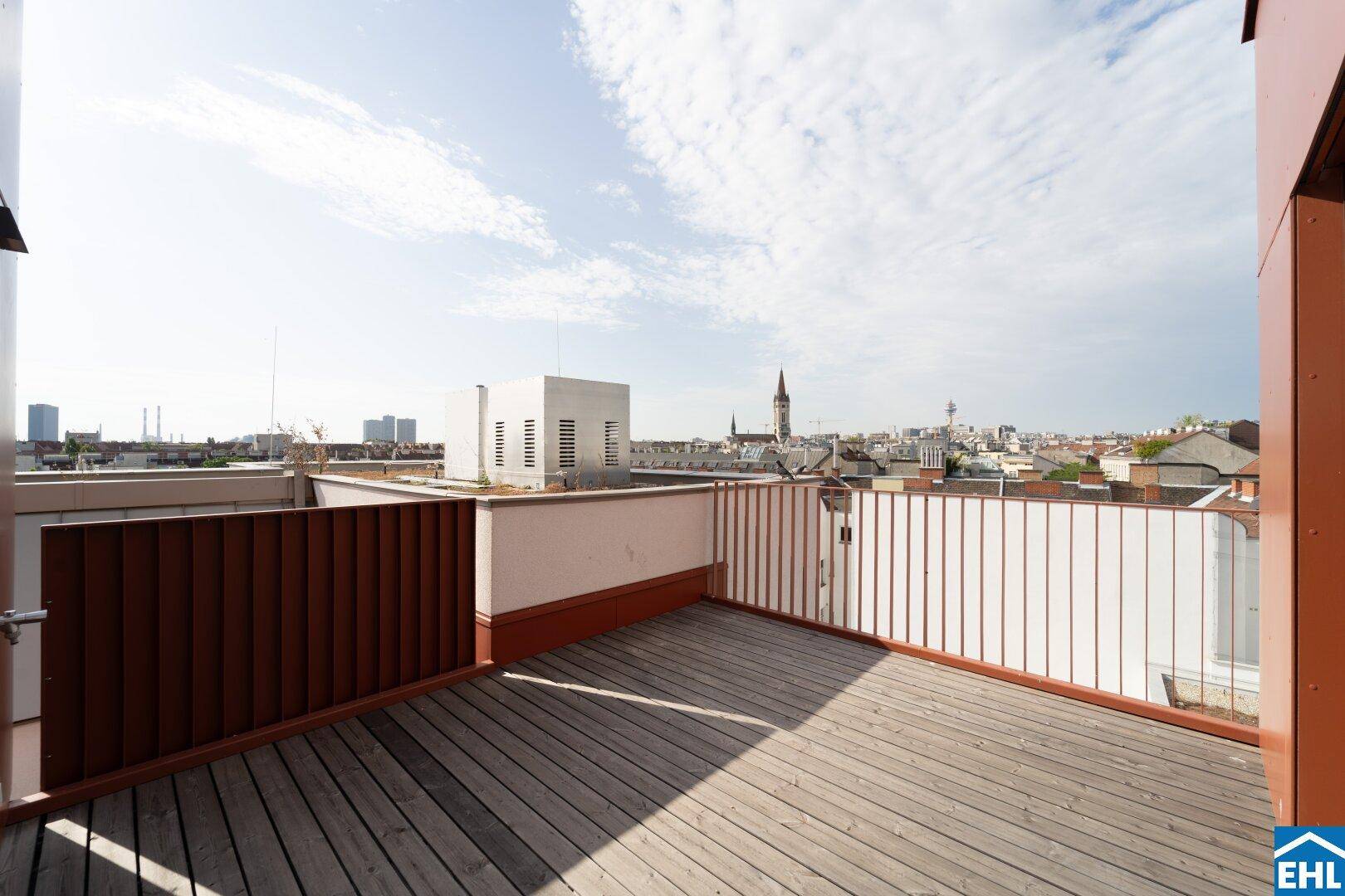 Große Dachterrasse mit Holzboden und weitem Blick über die Stadt.