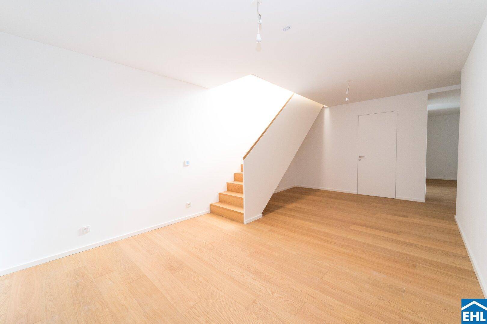 Heller, offener Raum mit Holztreppe und Parkettboden, ideal für einen Wohnbereich.