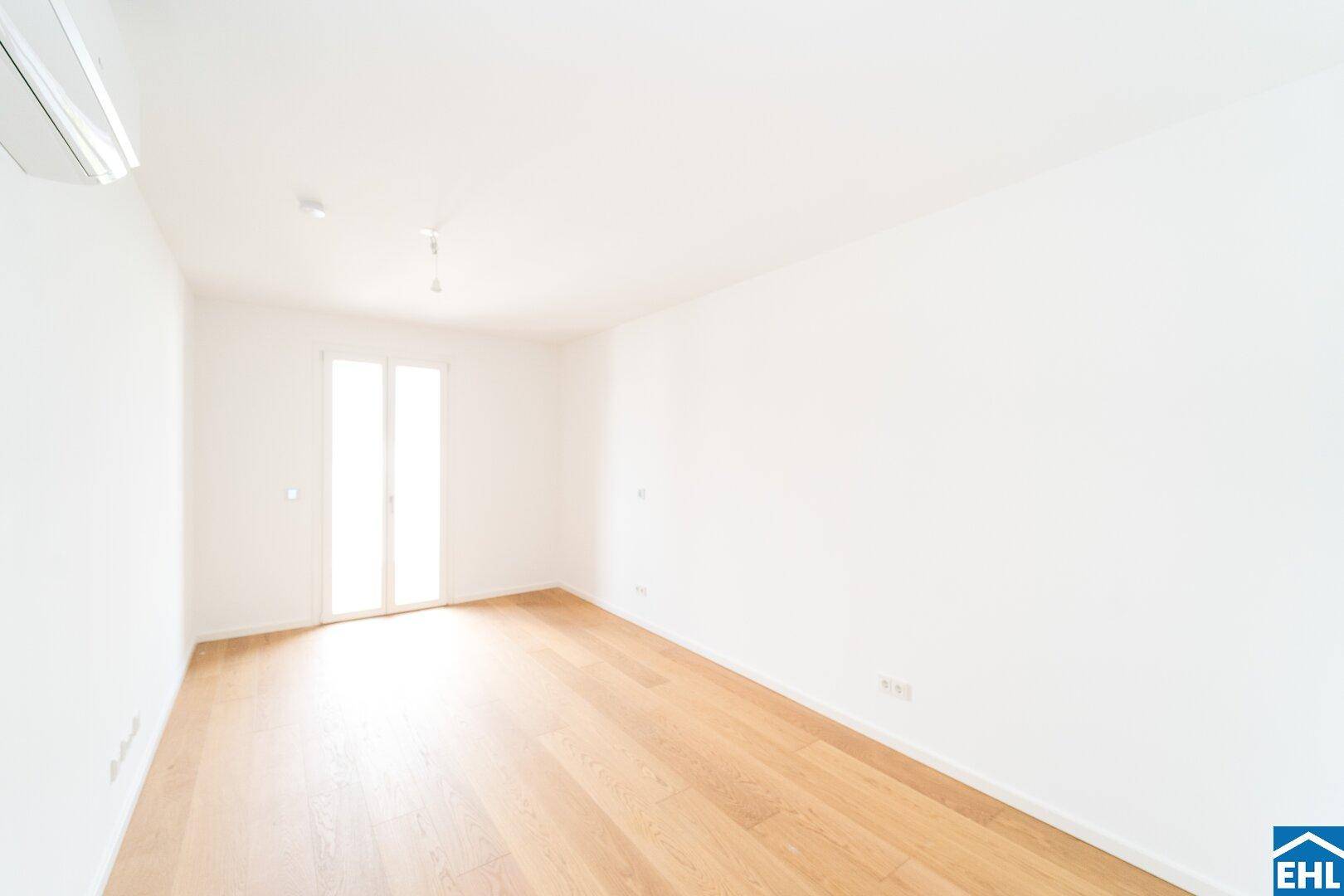 Helles Schlafzimmer mit Parkettboden und Zugang zu einem französischen Balkon oder kleiner Terrasse.