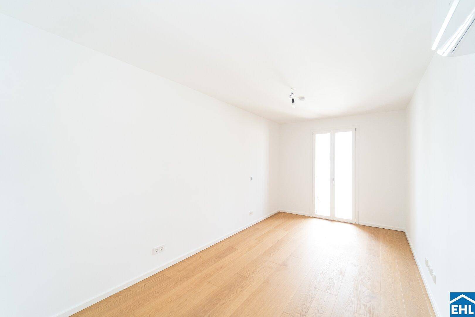 Geräumiges Schlafzimmer mit Klimaanlage und viel Tageslicht durch die Fenstertür.