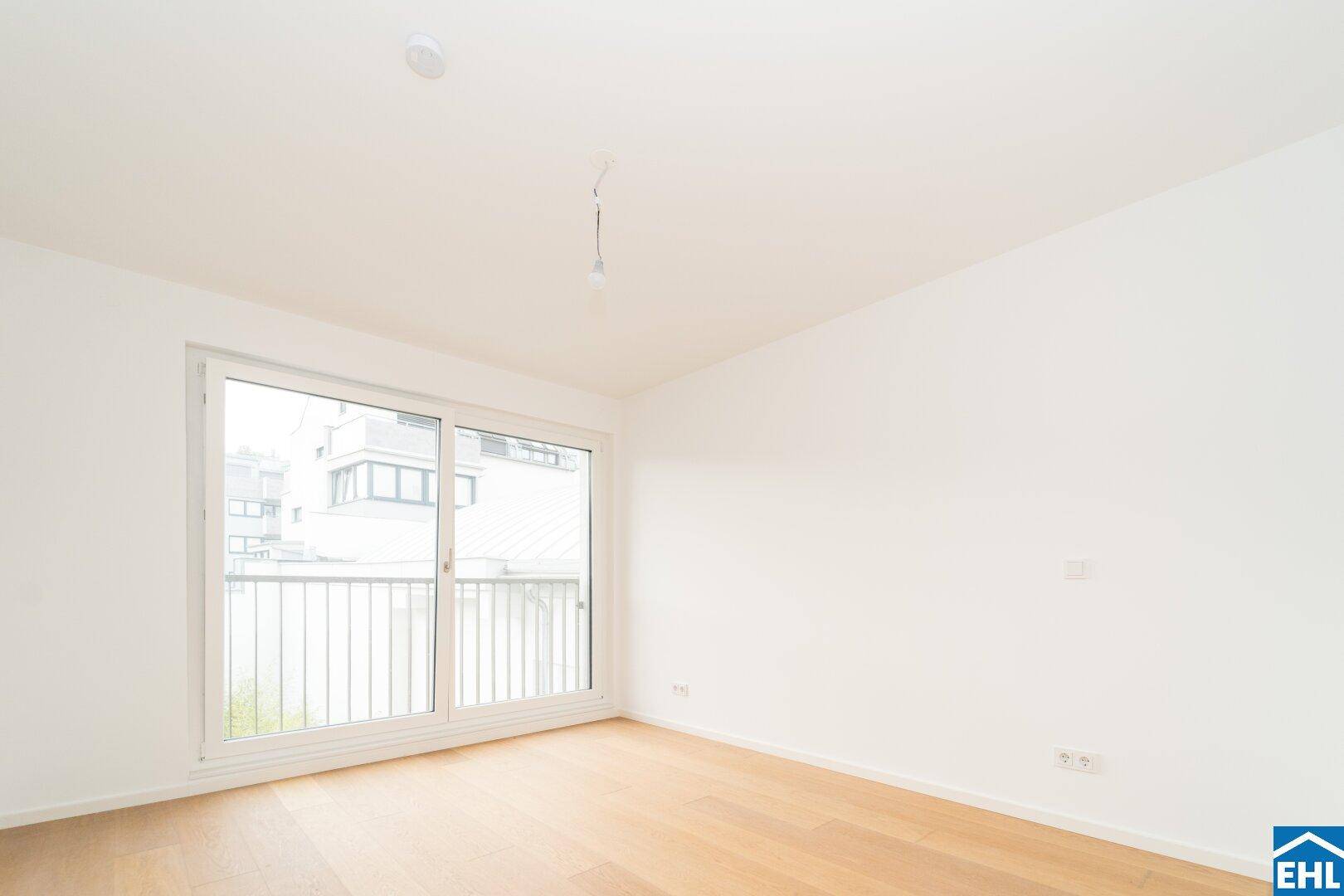 Heller Raum mit Holzboden und Zugang zu einem Balkon, ideal für ein Schlafzimmer.