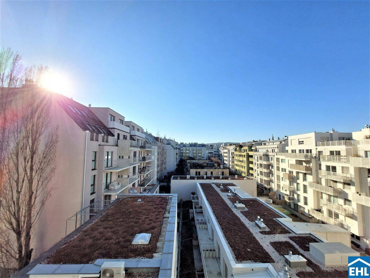 Weitläufiger Blick über die Dächer der Stadt mit modernen Wohngebäuden und begrünten Flachdächern.