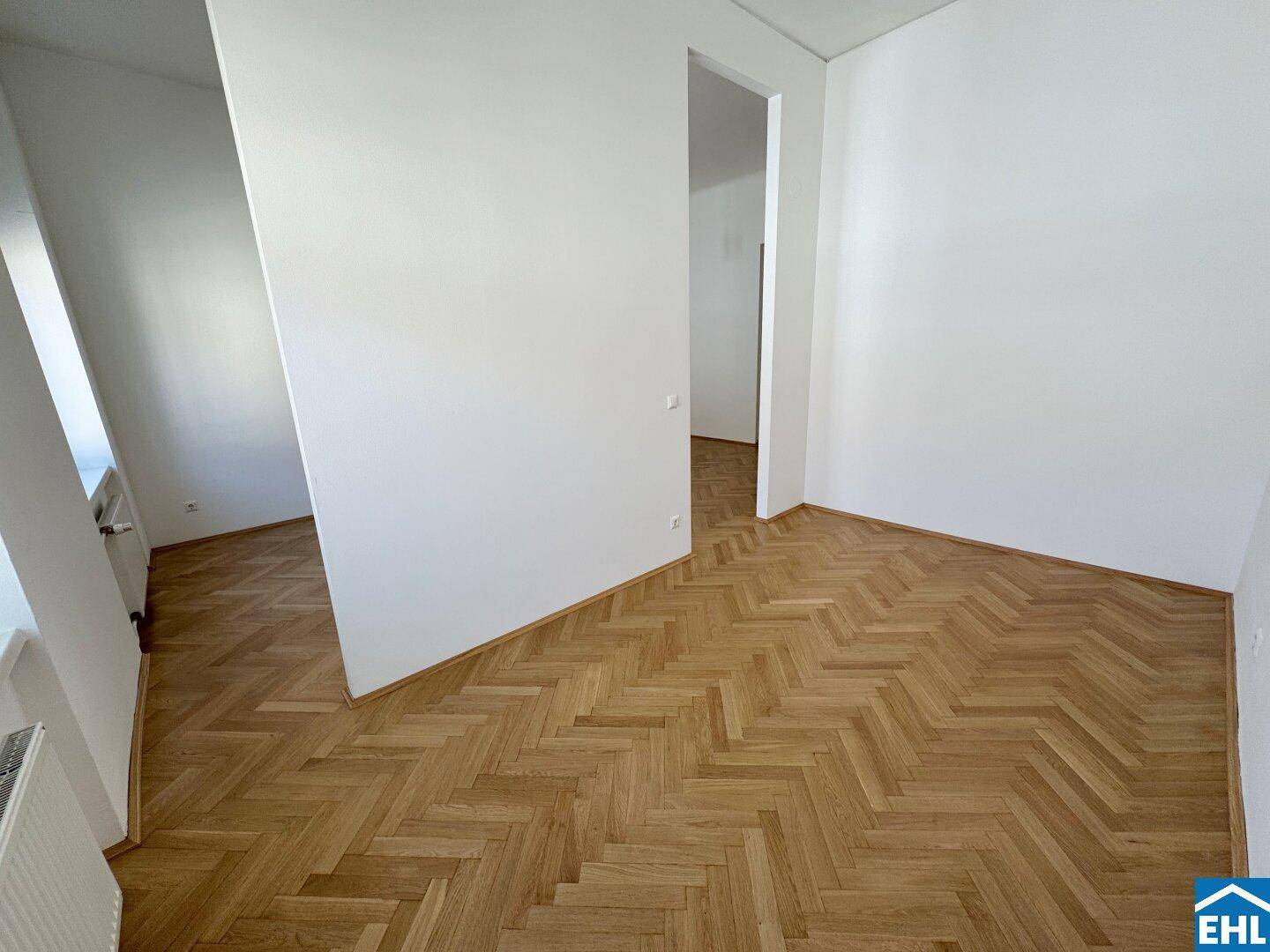 Ein weiterer Blick in den hellen Wohnbereich mit klassischem Fischgrätparkett und klaren Linien.