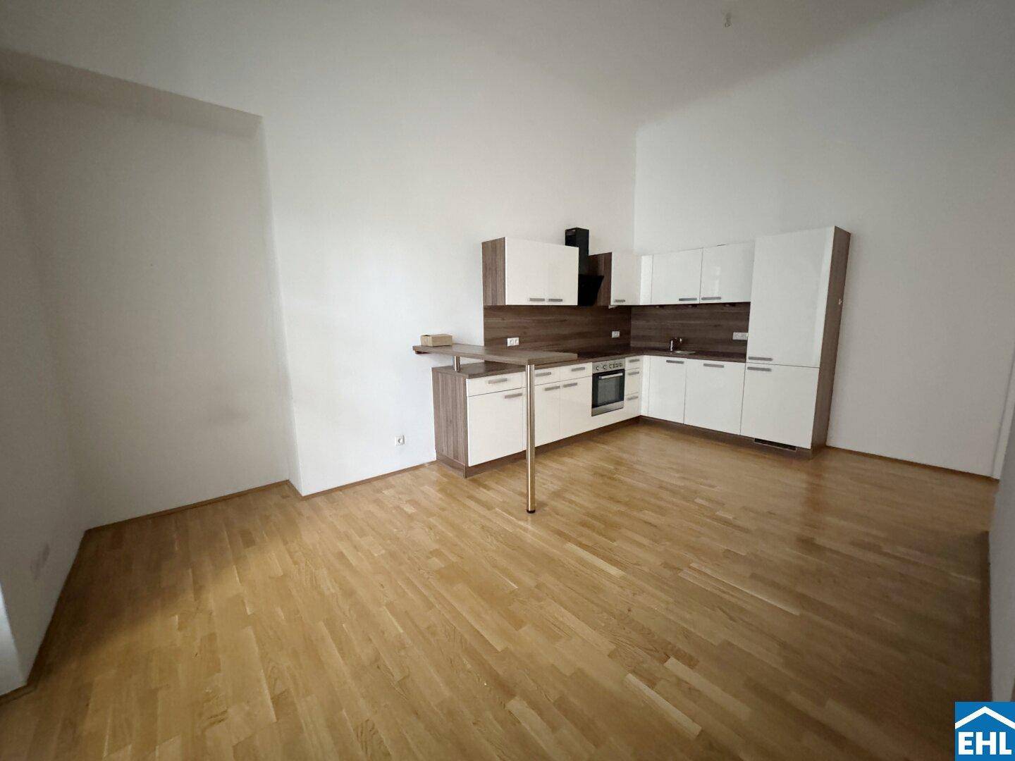 Weitläufige Ansicht einer modernen, weißen Küche mit Holzakzenten und einem kleinen Frühstücksbereich.