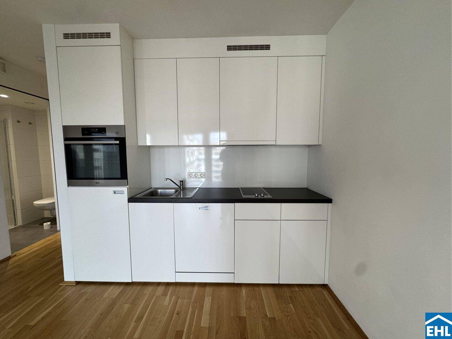 Kompakte, moderne Küchenzeile mit Spüle, Kochfeld und integriertem Backofen, ideal für kleine Wohnungen.