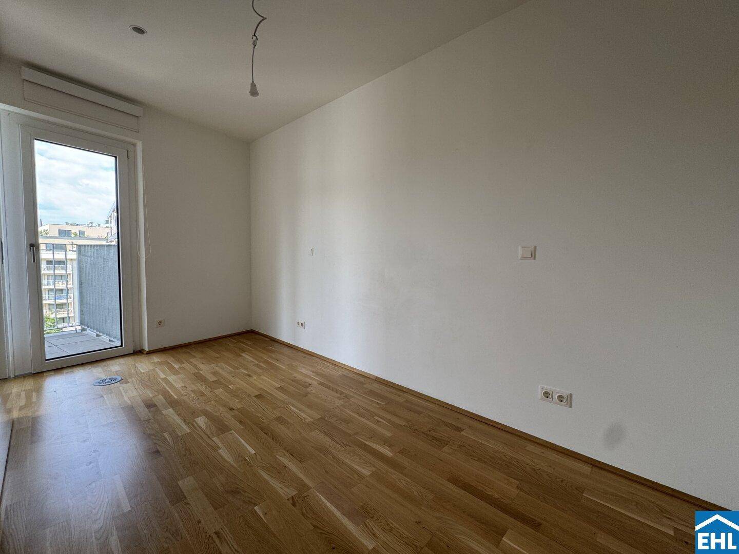 Helles Schlafzimmer mit Zugang zum Balkon und Parkettboden, bietet eine angenehme Wohnatmosphäre.