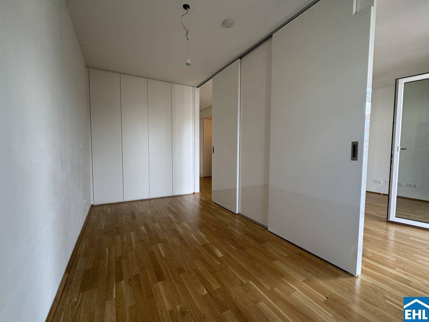 Schlafzimmer mit hellem Parkettboden und praktischen Einbauschränken, die viel Stauraum bieten.