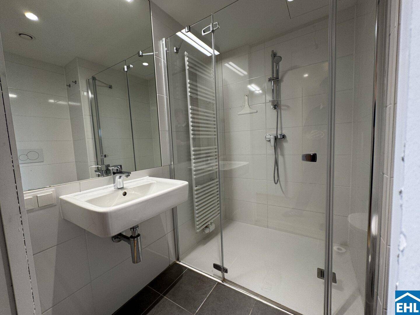 Modernes Badezimmer mit ebenerdiger Dusche, Wand-WC und beheiztem Handtuchhalter.