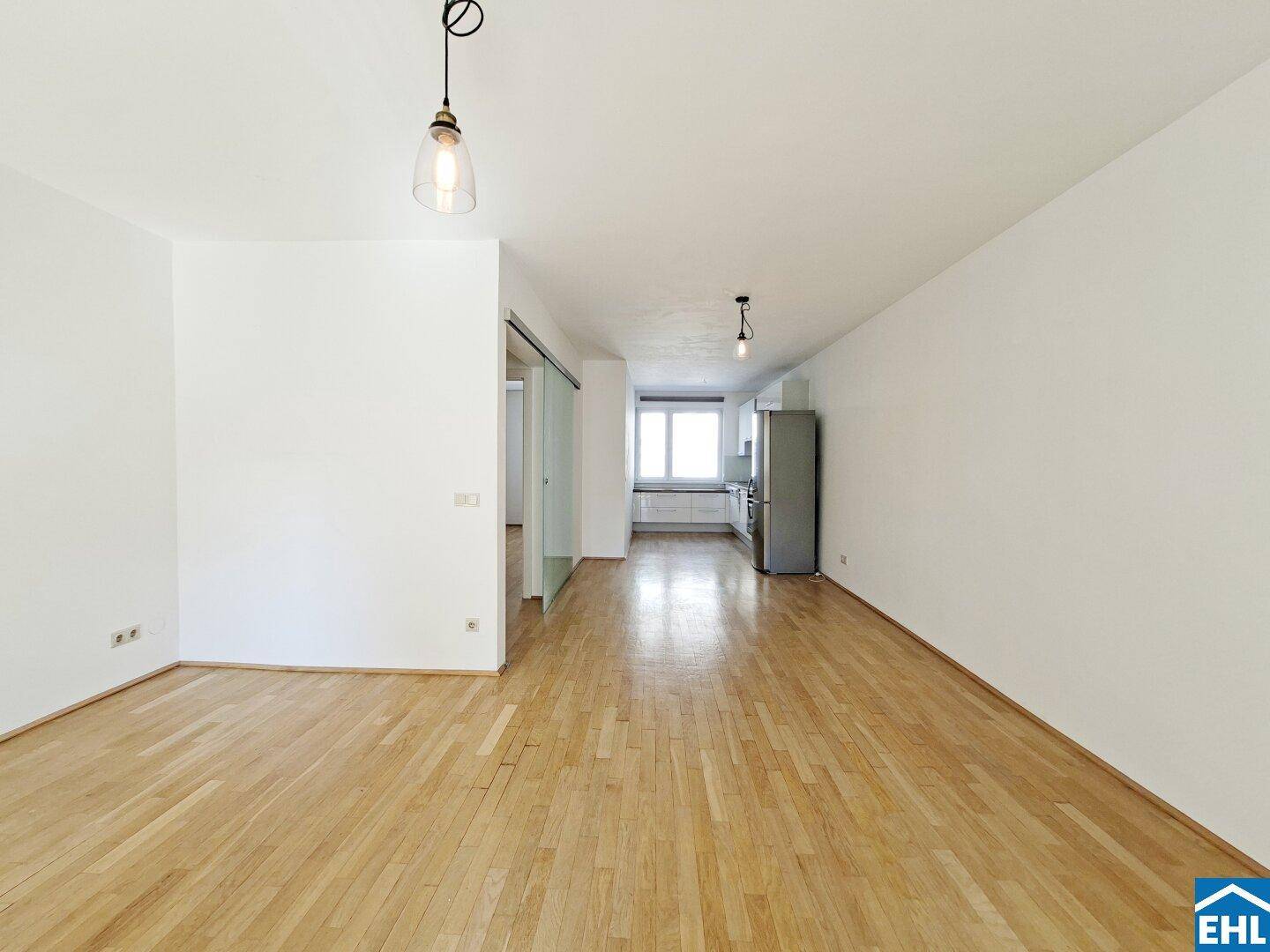 Geräumiger Wohnbereich mit Holzboden und offener Verbindung zur Küche.
