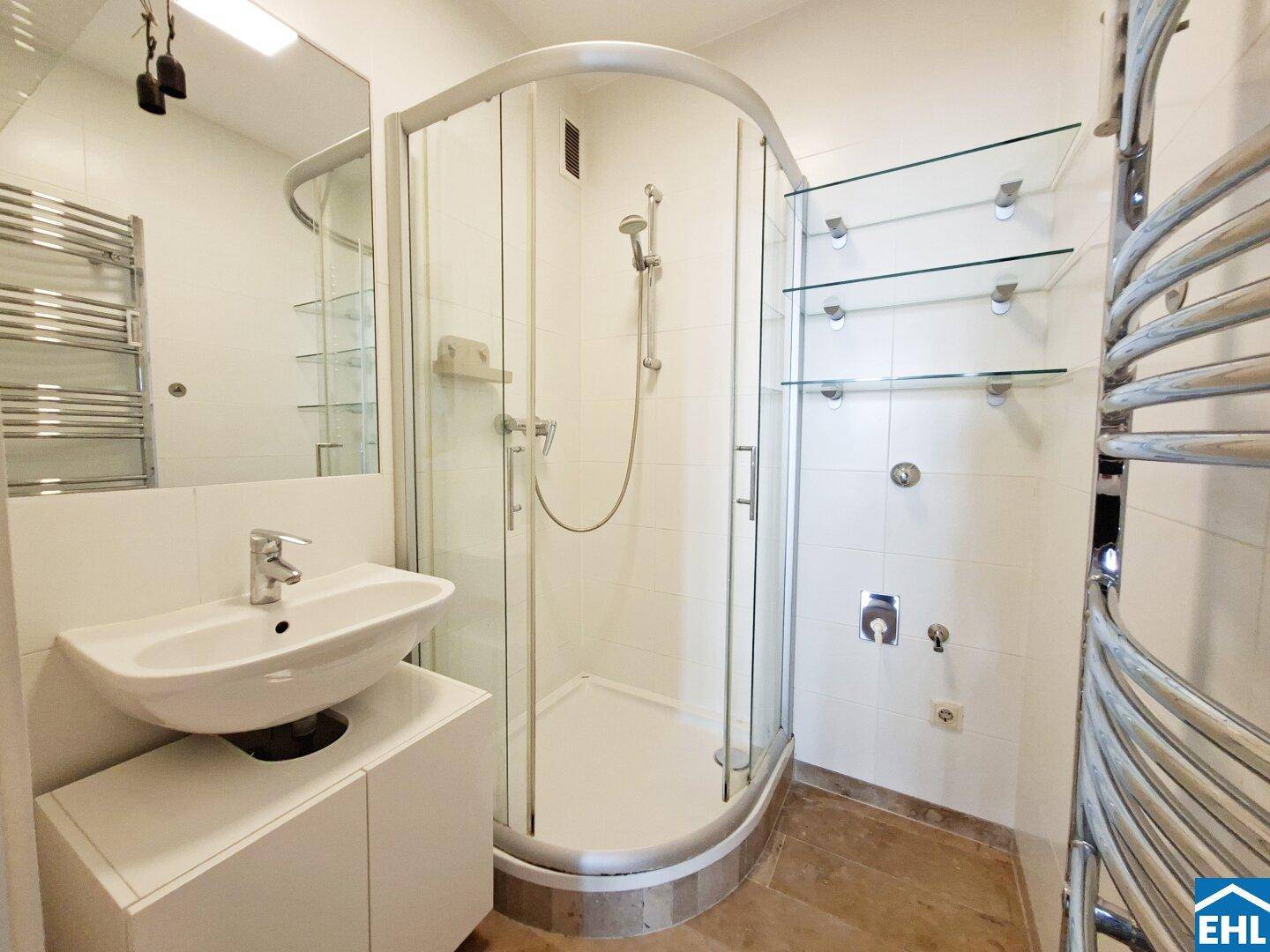Modernes Badezimmer mit Duschkabine, Waschbecken und beheiztem Handtuchhalter.