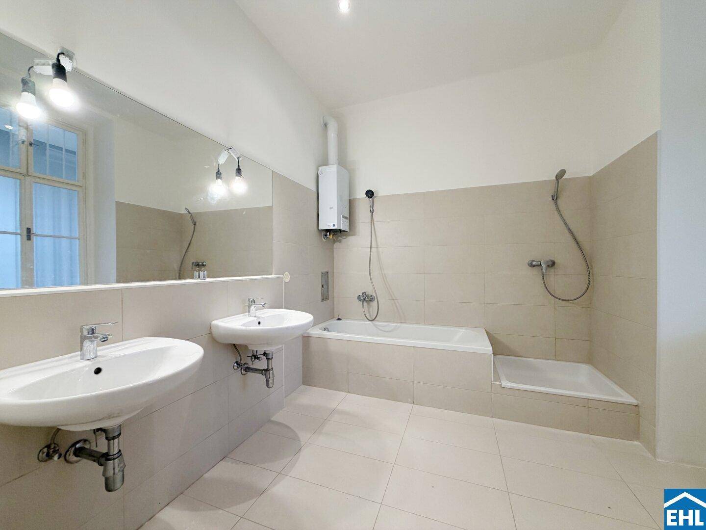 Geräumiges Badezimmer mit zwei Waschbecken, Badewanne und Duschbereich, hell gefliest.