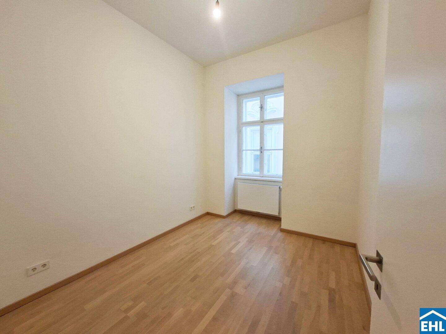 Helles, leeres Zimmer mit Parkettboden und einem Fenster, bereit zur individuellen Einrichtung.