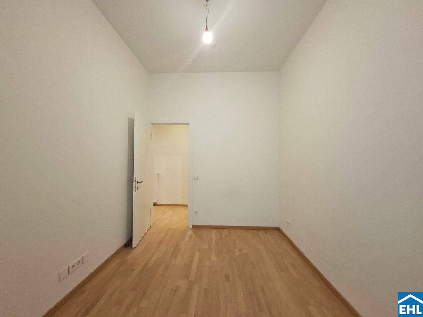 Leeres Zimmer mit hellem Parkettboden und weiß gestrichenen Wänden, bietet vielseitige Nutzungsmöglichkeiten.