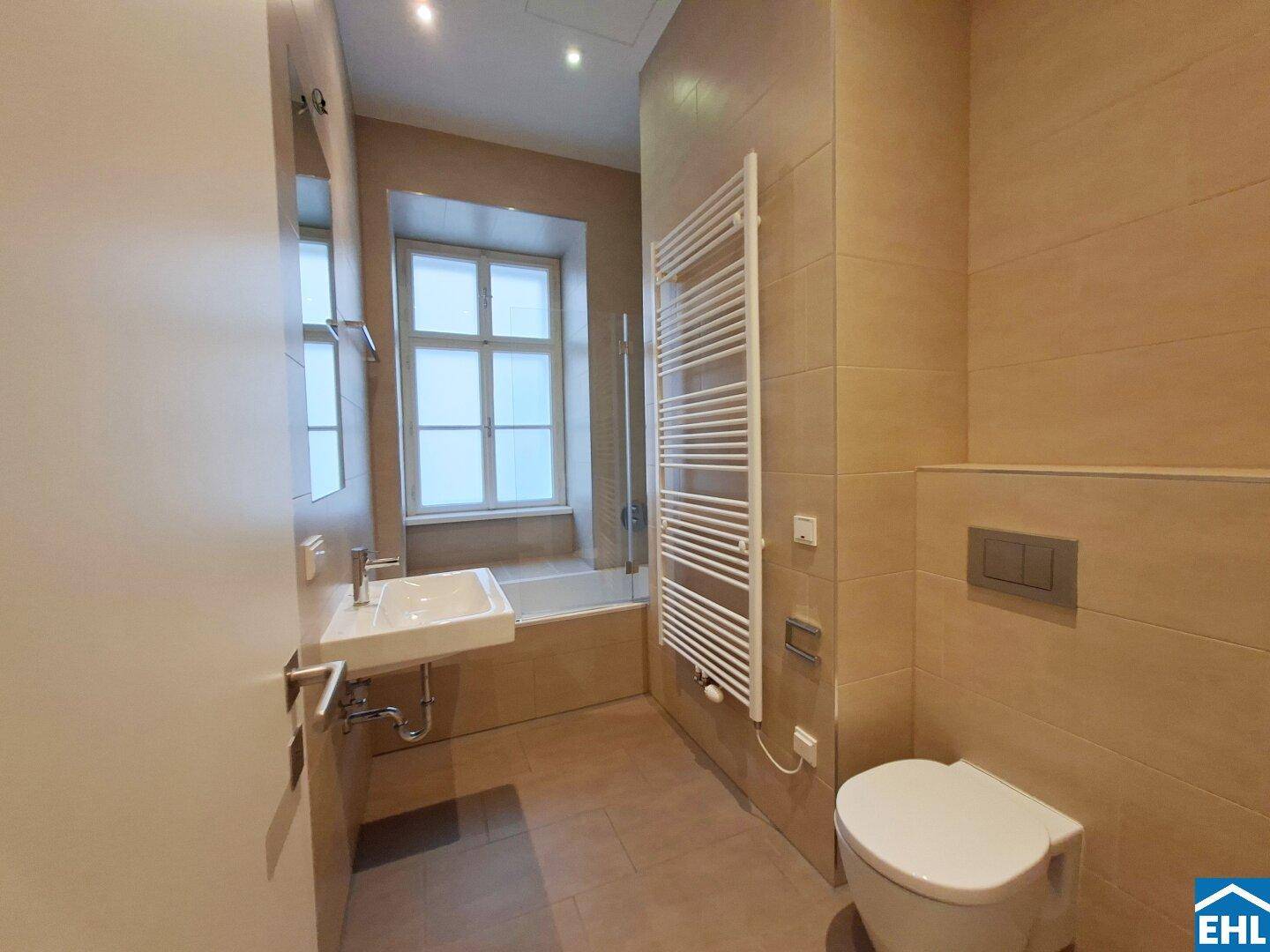 Modernes Badezimmer mit Badewanne, wandhängendem WC und beheiztem Handtuchhalter.