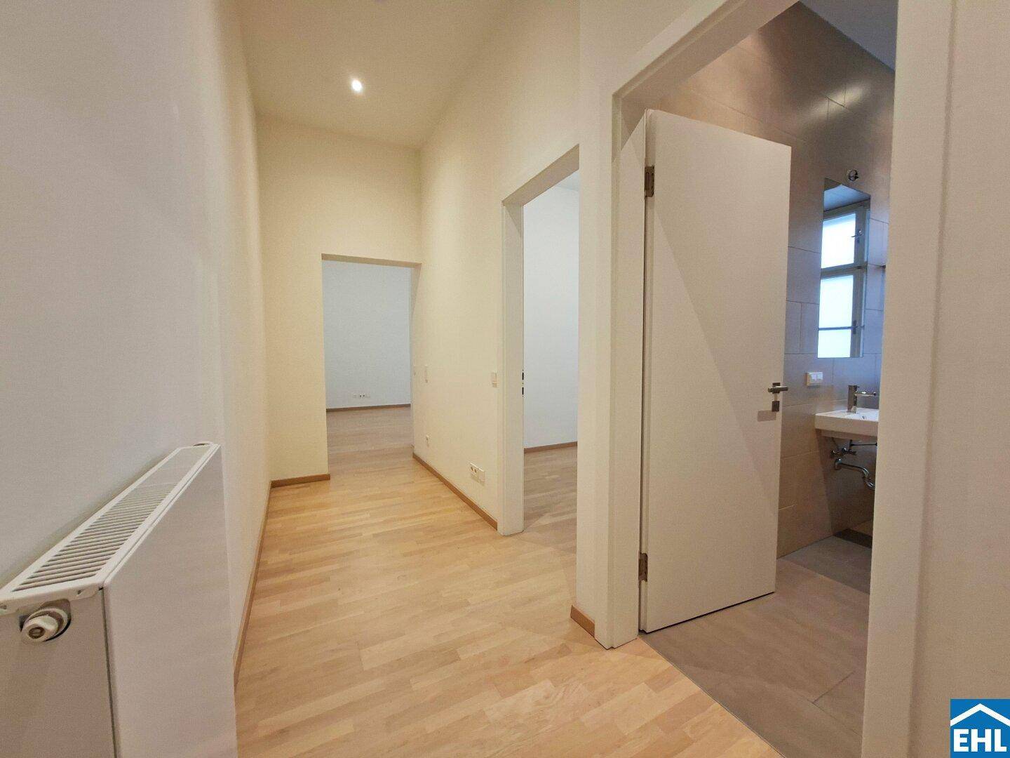 Heller Flur mit Parkettboden und Zugang zu verschiedenen Zimmern, inklusive Badezimmer.