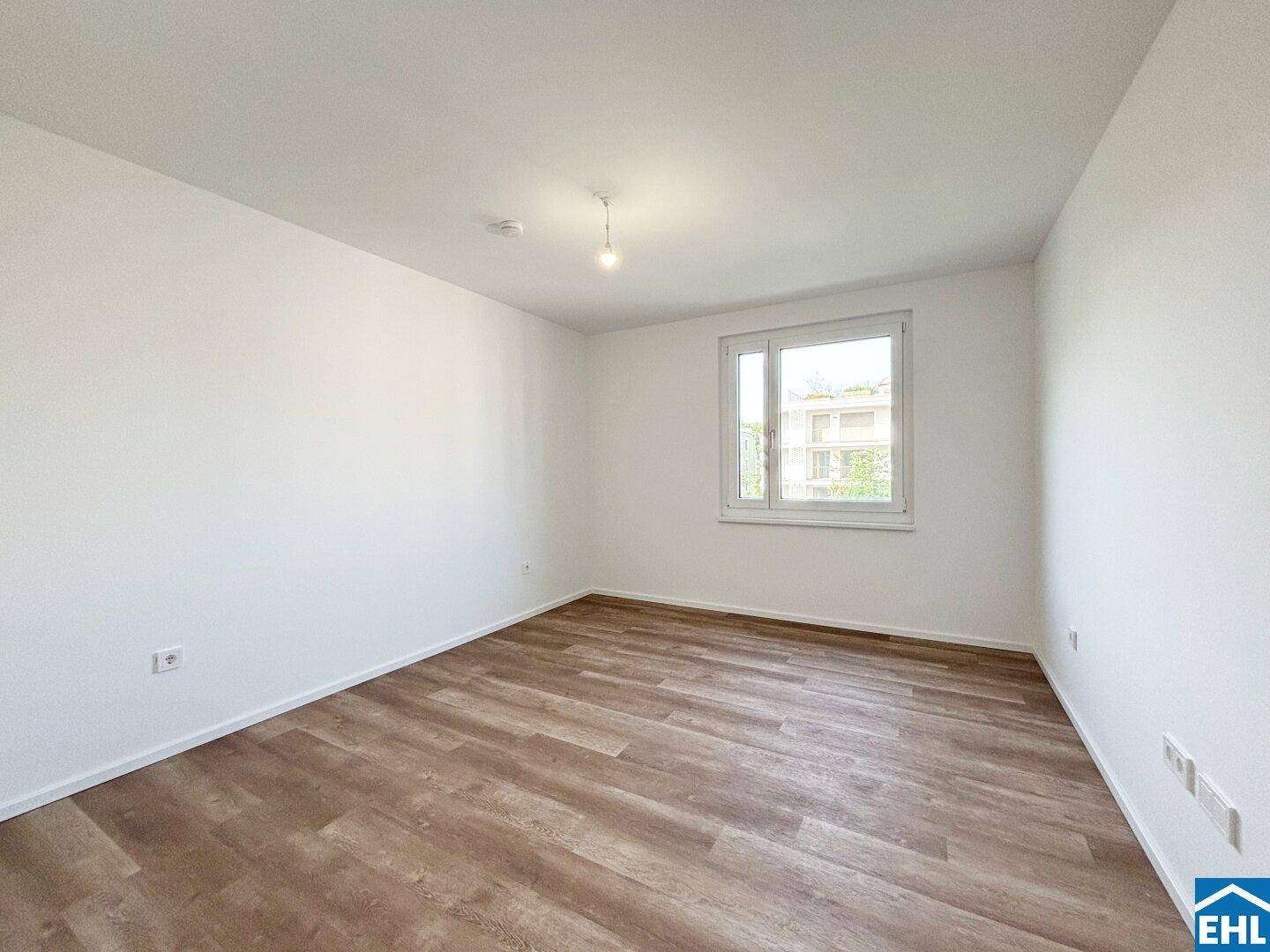 Helles Schlafzimmer mit Laminatboden und großem Fenster, bereit zur Einrichtung.