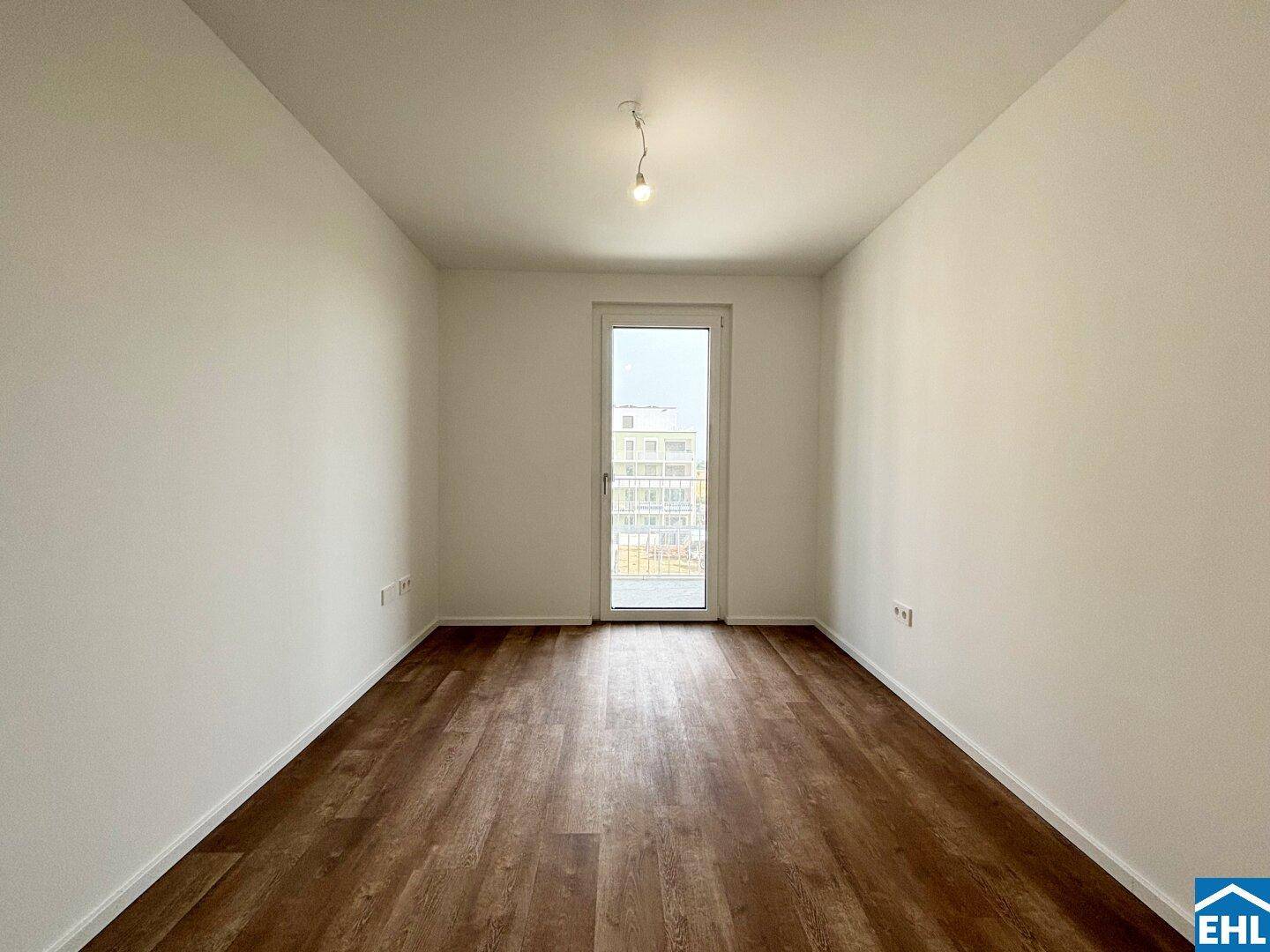 Geräumiges Zimmer mit Laminatboden und Zugang zu einem französischen Balkon.
