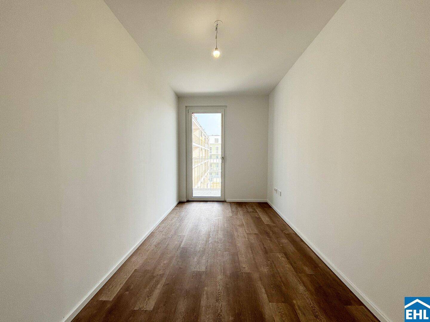 Lichtdurchflutetes Zimmer mit Laminatboden und Tür zum Außenbereich.