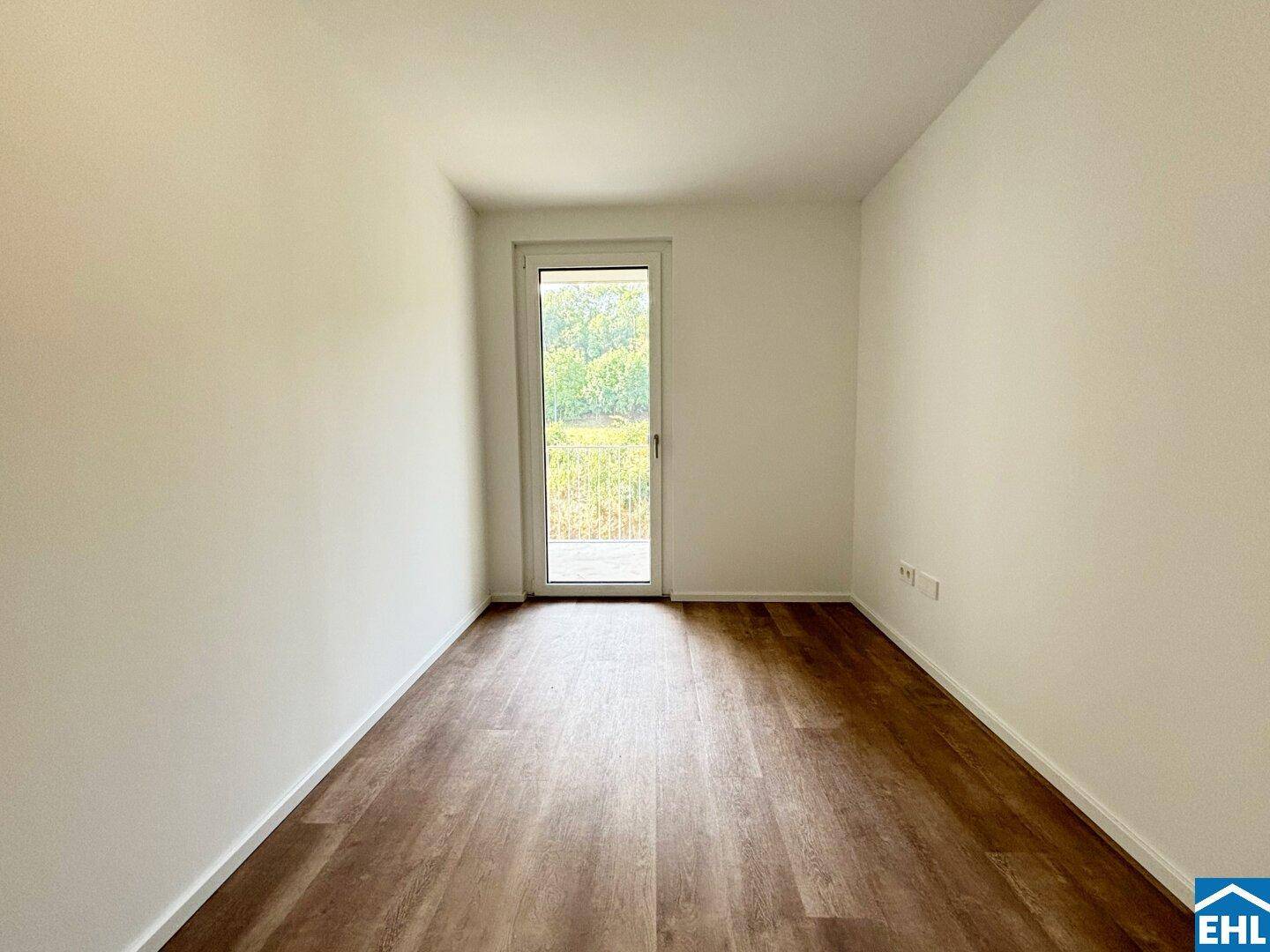 Helles Zimmer mit Laminatboden und direktem Zugang zu einem Balkon.