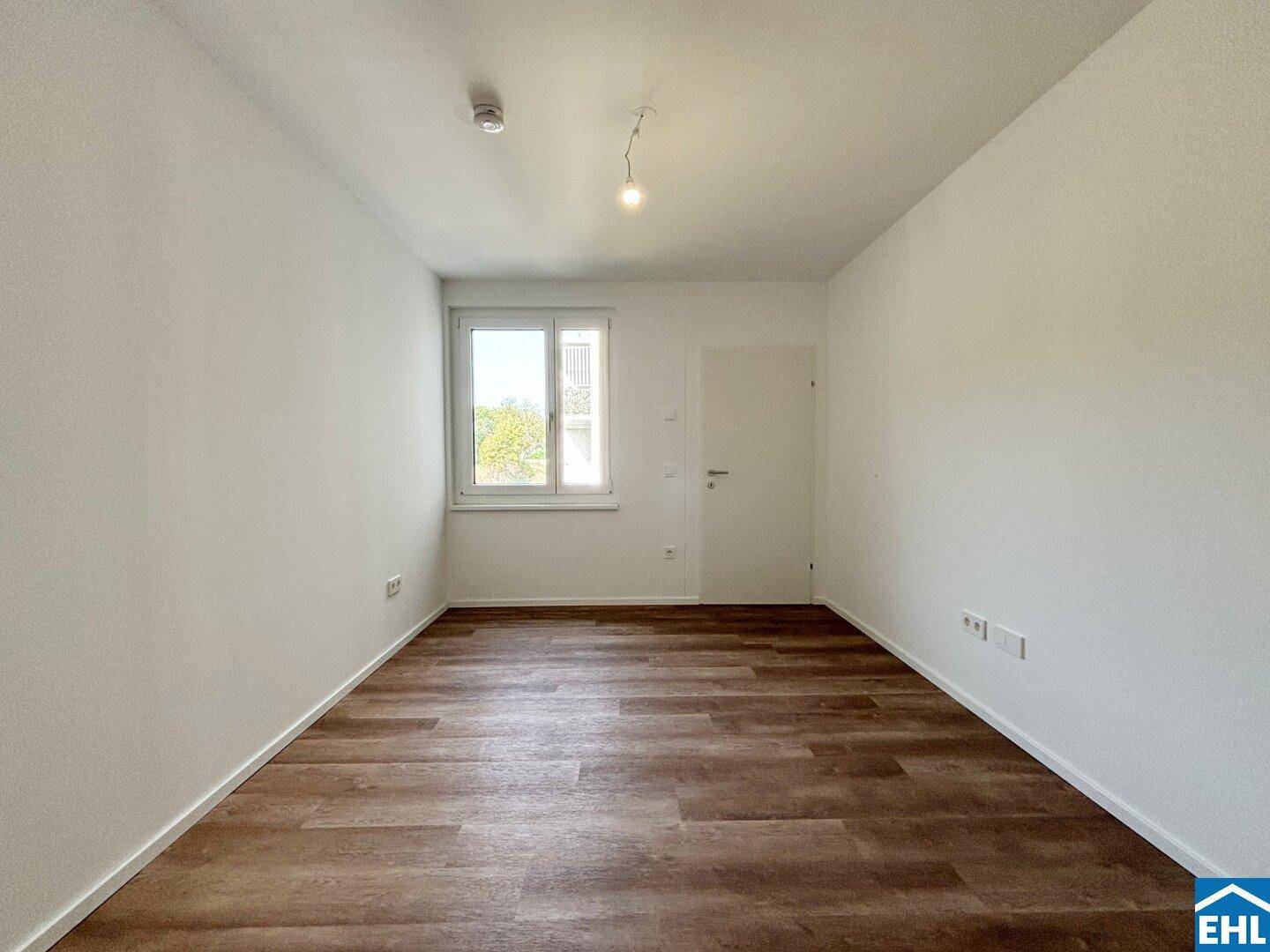 Freundliches Zimmer mit großem Fenster und strapazierfähigem Laminatboden.
